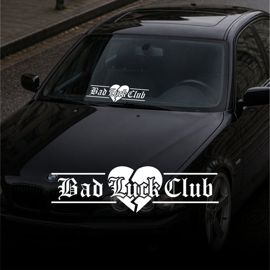Black car with 'Bad Luck Club' heart-shaped decal on a dark background