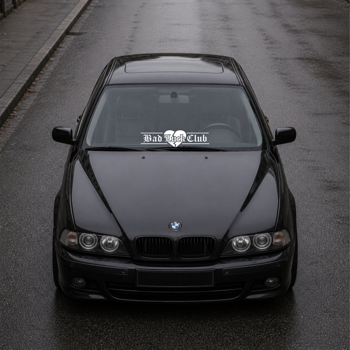 Black BMW car on a road with 'Bad Bitch Club' decal.