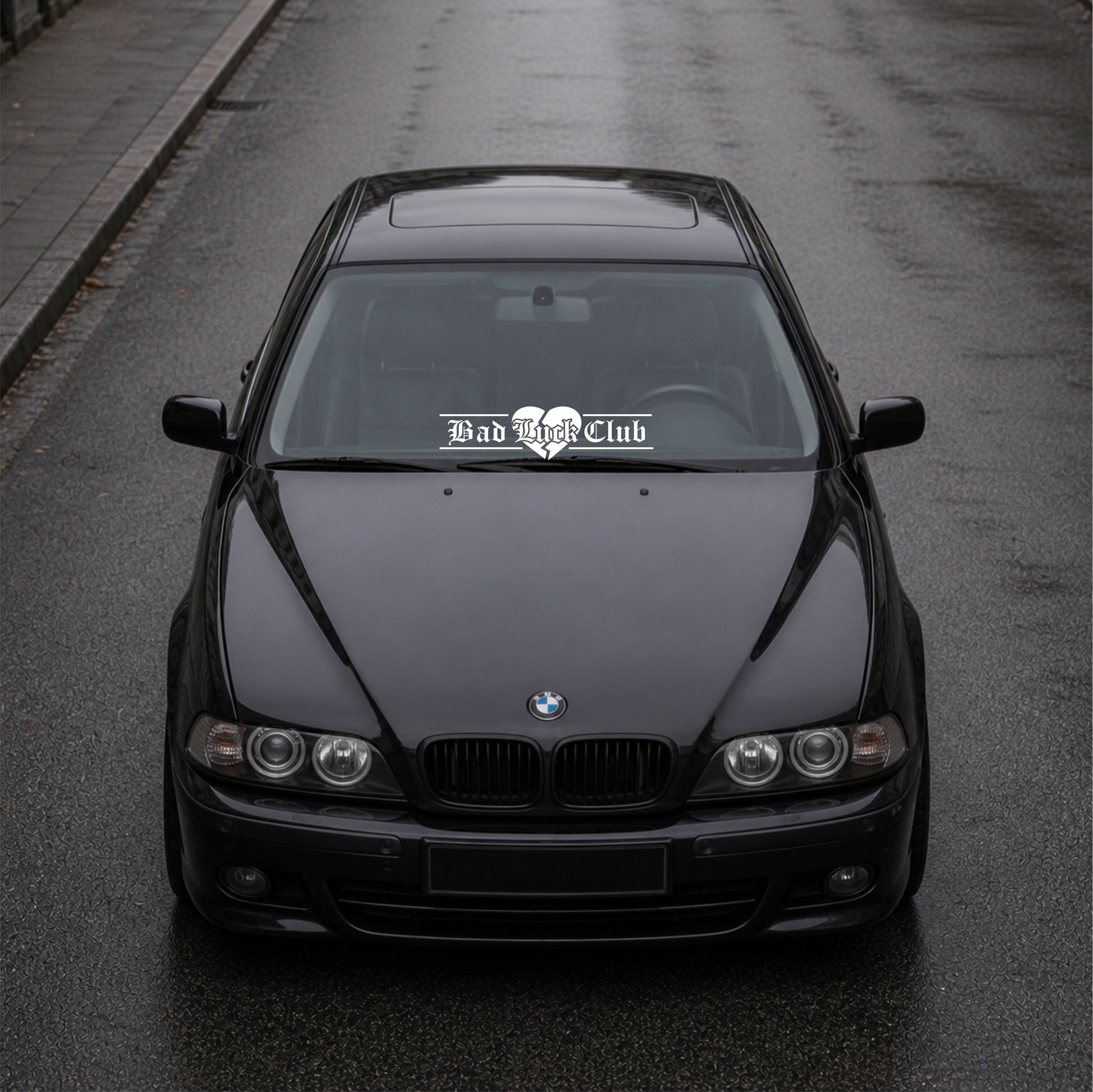 Black BMW car on a road with 'Bad Bitch Club' decal.