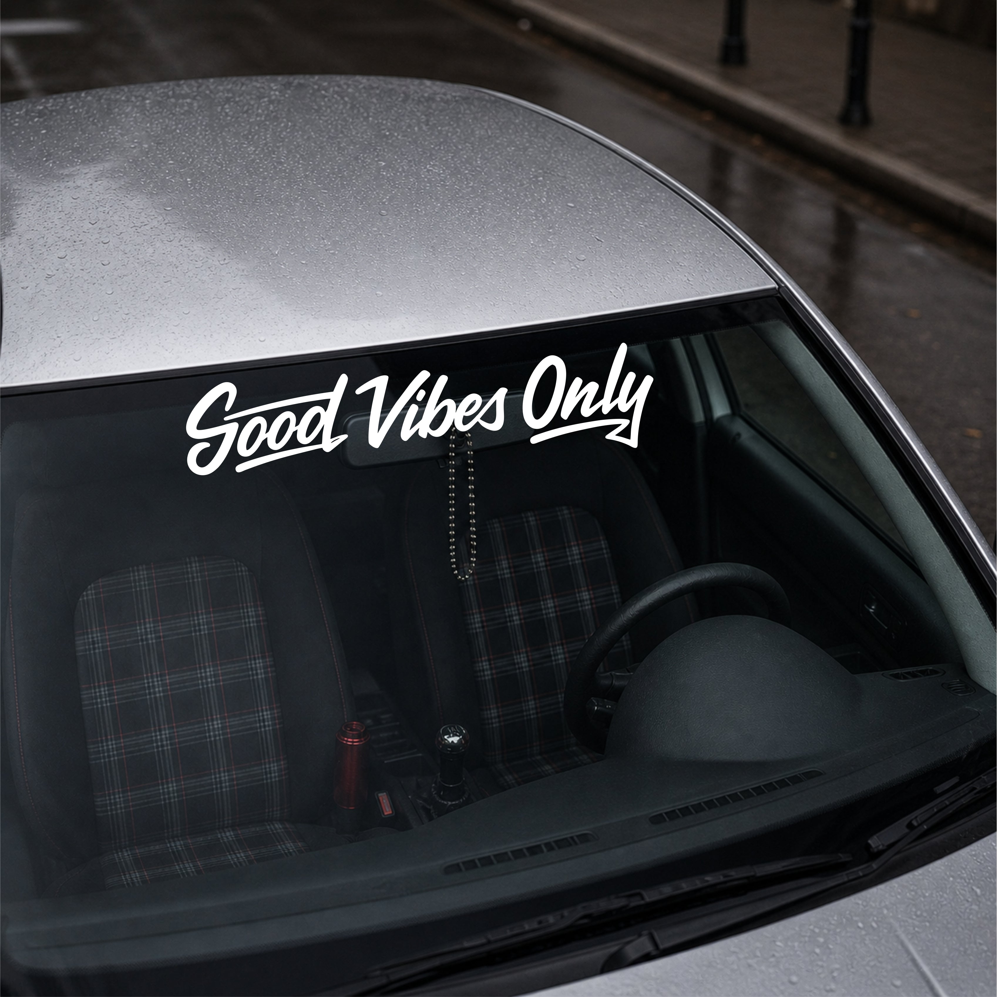Car interior with 'Good Vibes Only' decal on the windshield