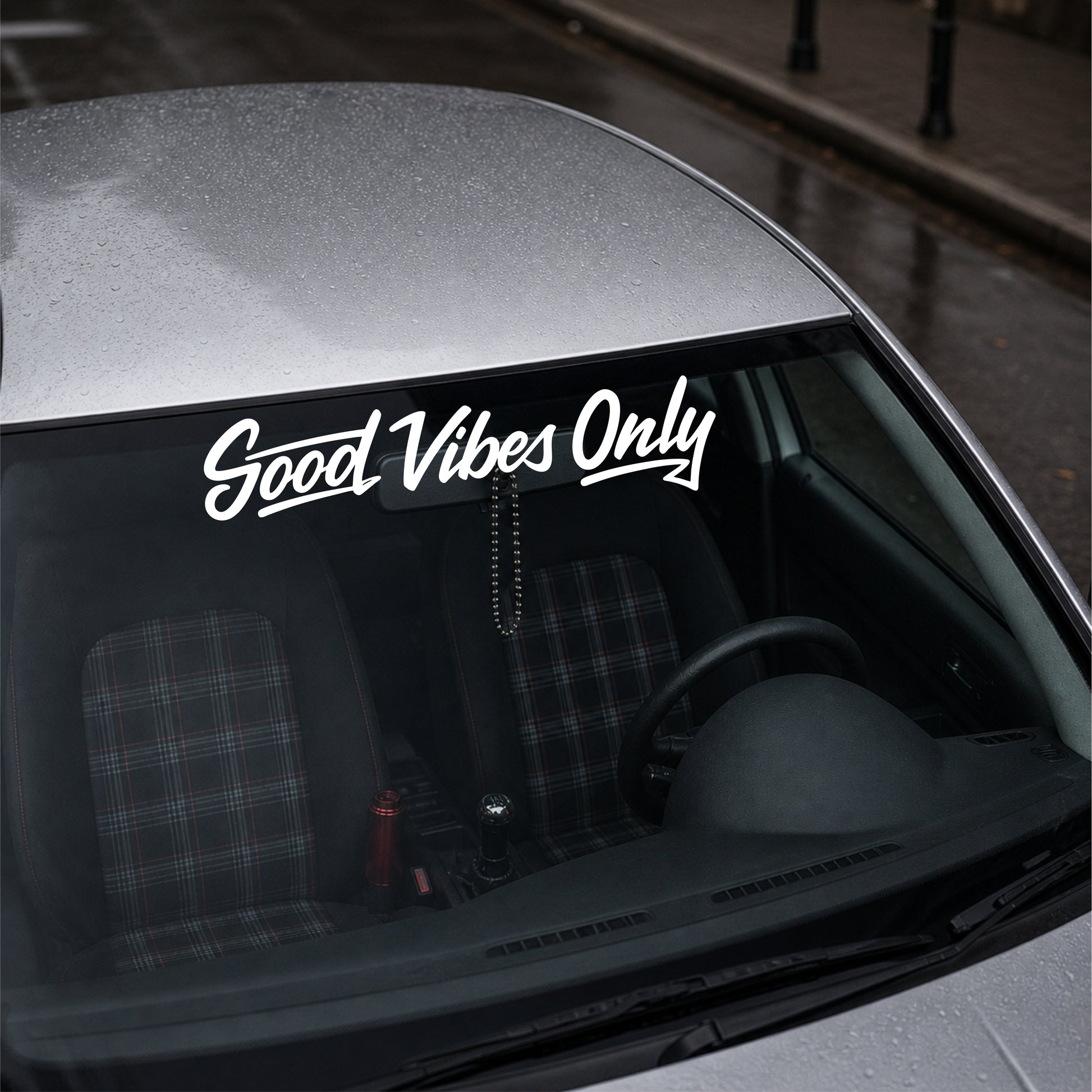 Car interior with 'Good Vibes Only' decal on the windshield