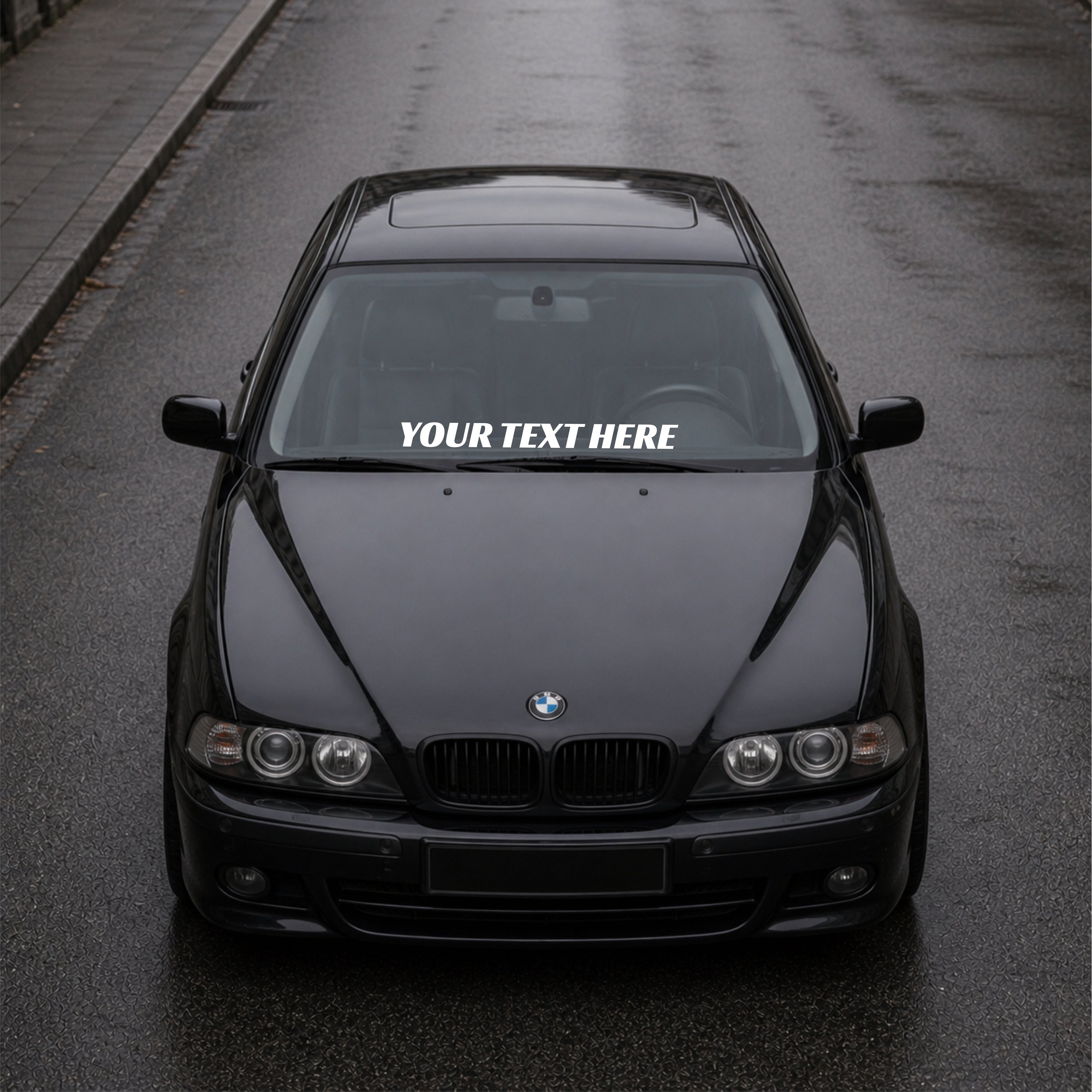 Black BMW car on a road with a decal on the windshield.
