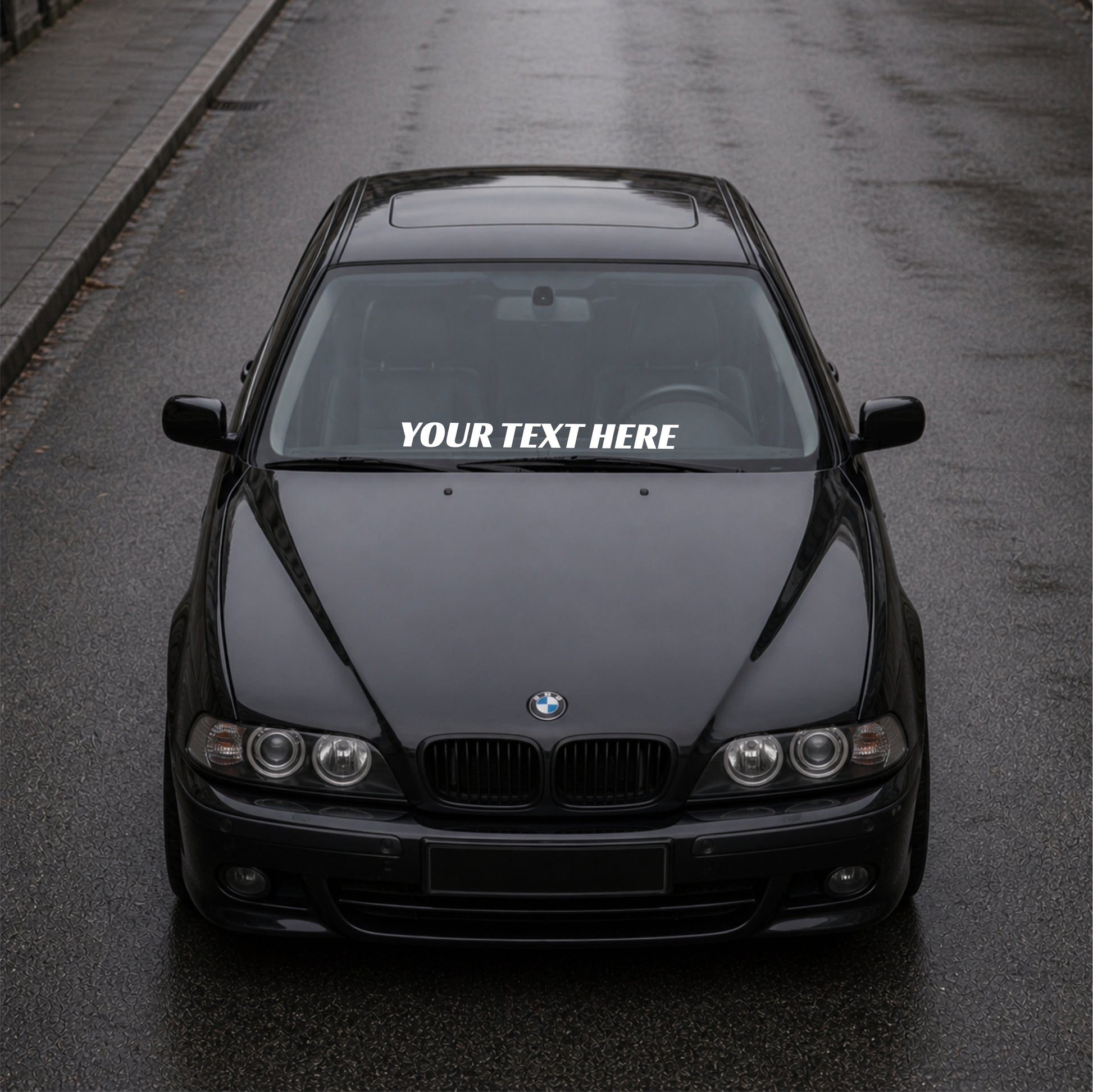 Black BMW car on a road with a decal on the windshield.