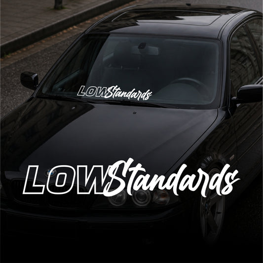 Black car with 'LOW Standards' branding on a blurred street background