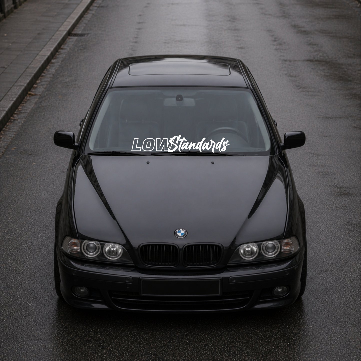 Black BMW car on a road with 'LOW Standards' decal.
