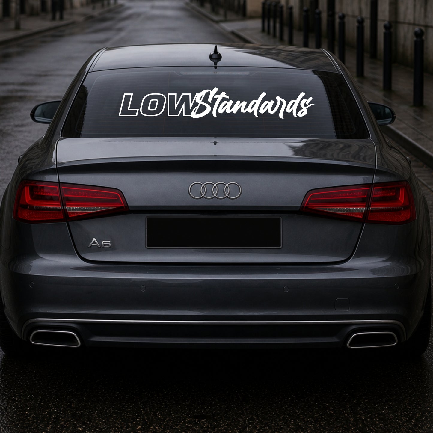 Audi car with 'LOW Standards' decal on the back window.