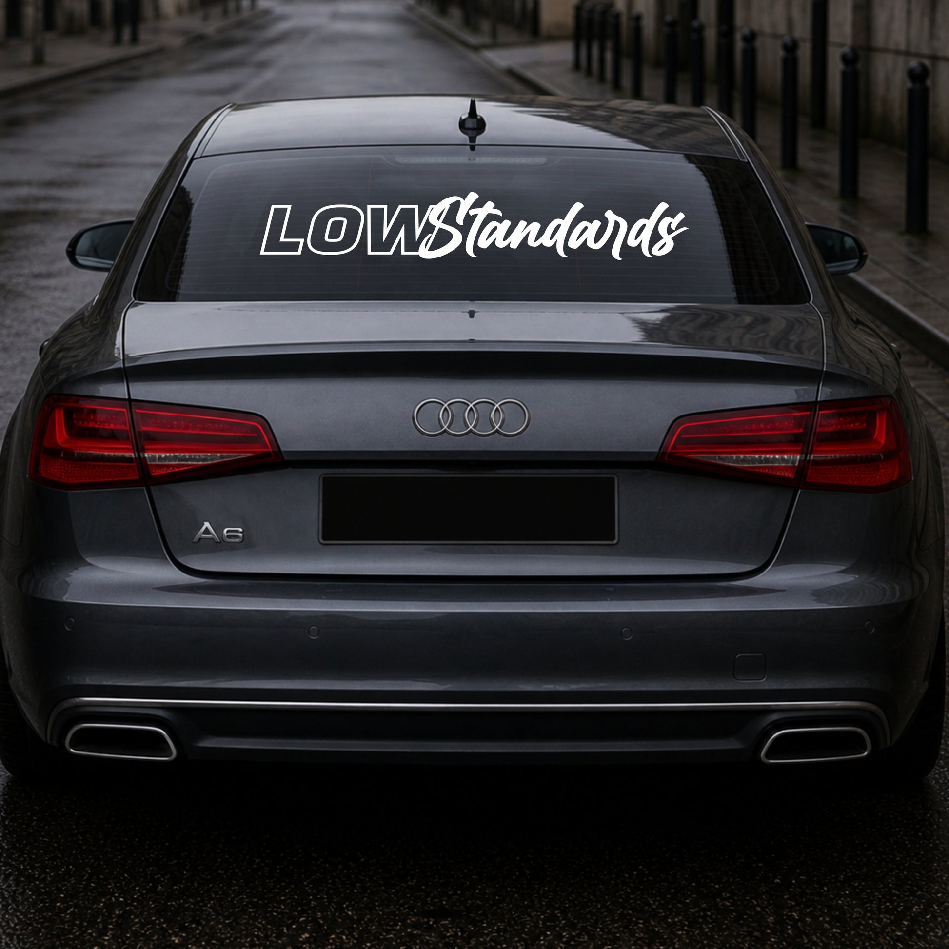 Audi car with 'LOW Standards' decal on the back window.