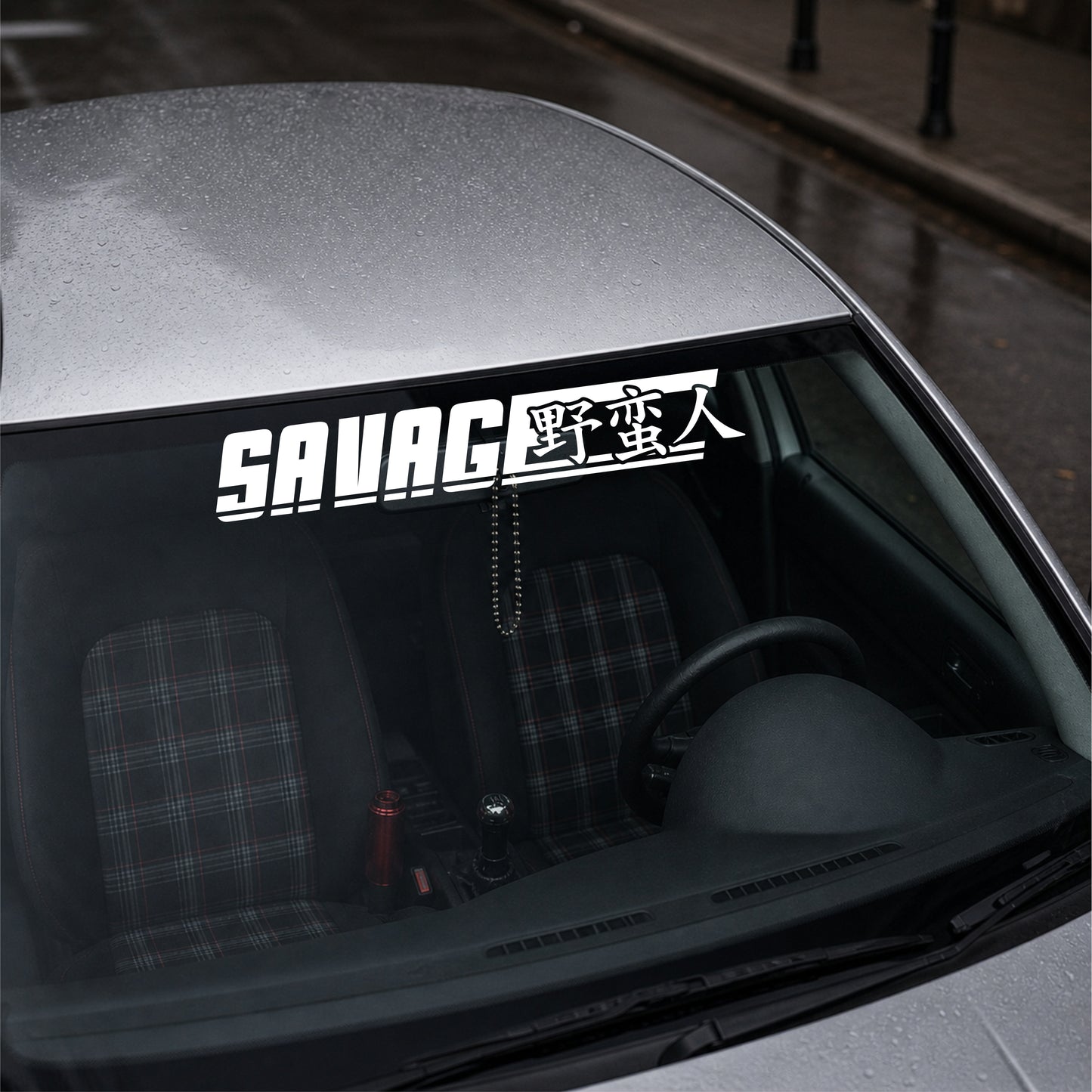 Car window with a 'SAVAGE' decal on a gray car interior.
