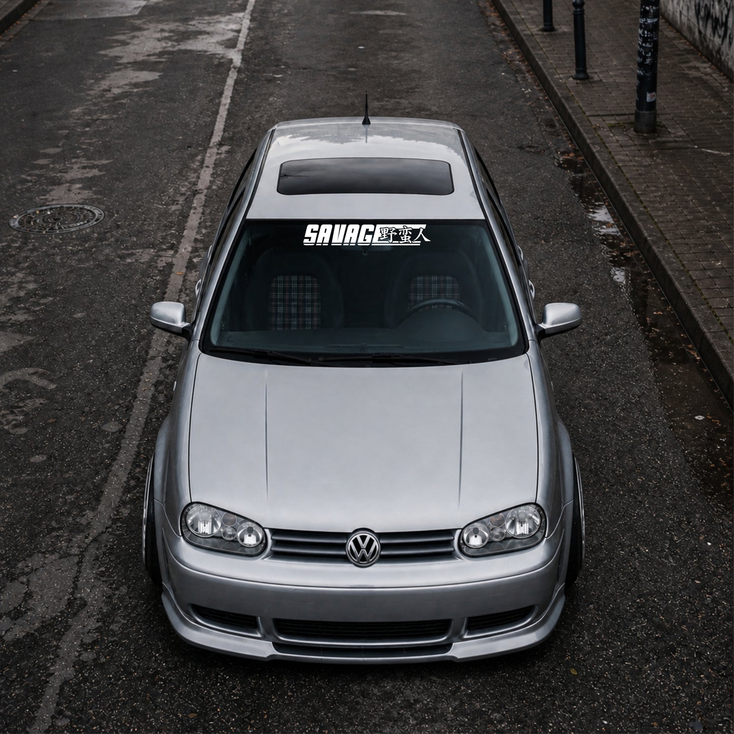 Silver Volkswagen car on a street with 'Savage' decal