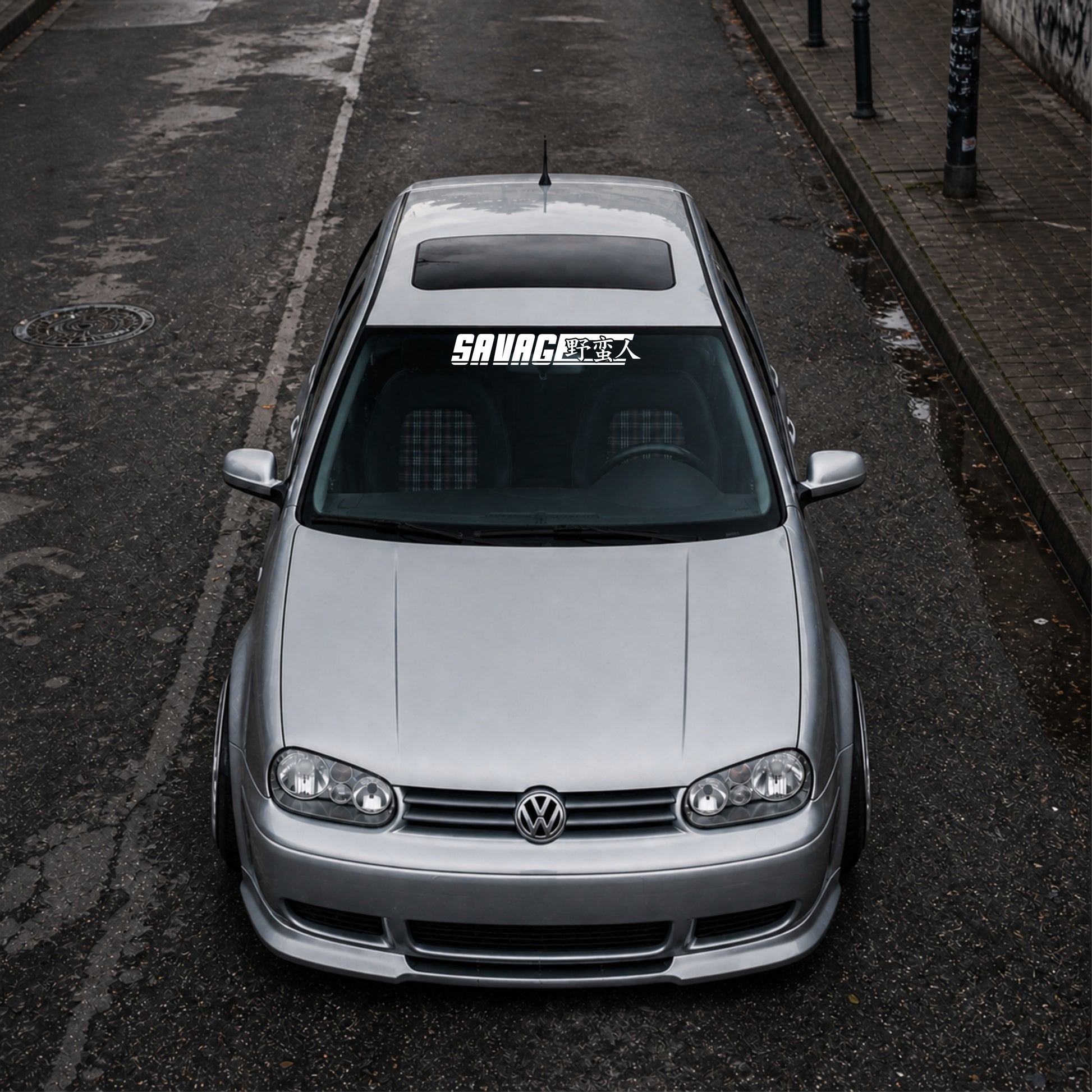 Silver Volkswagen car on a street with 'Savage' decal