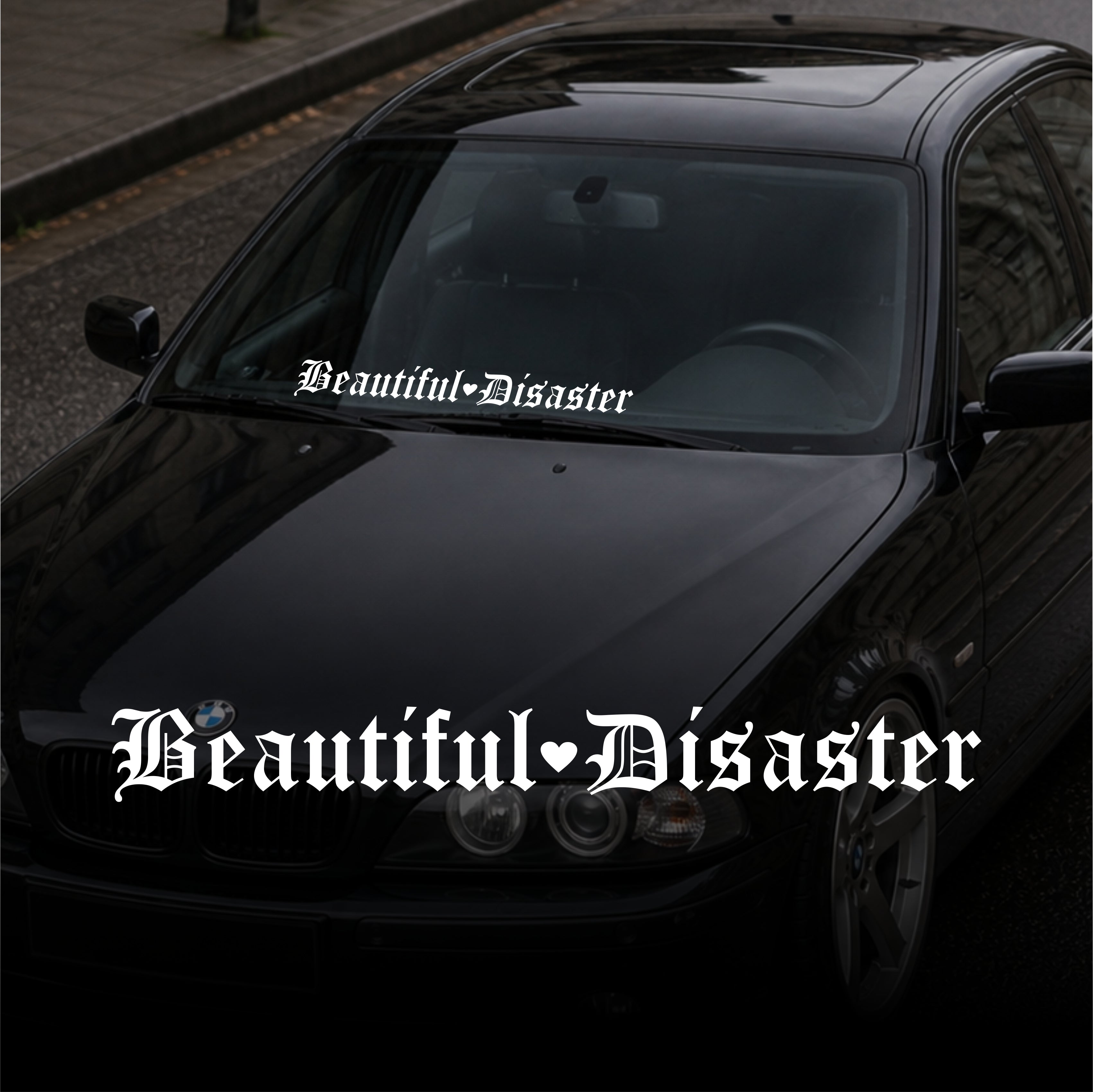 Black car with 'Beautiful Disaster' decal on a dark background