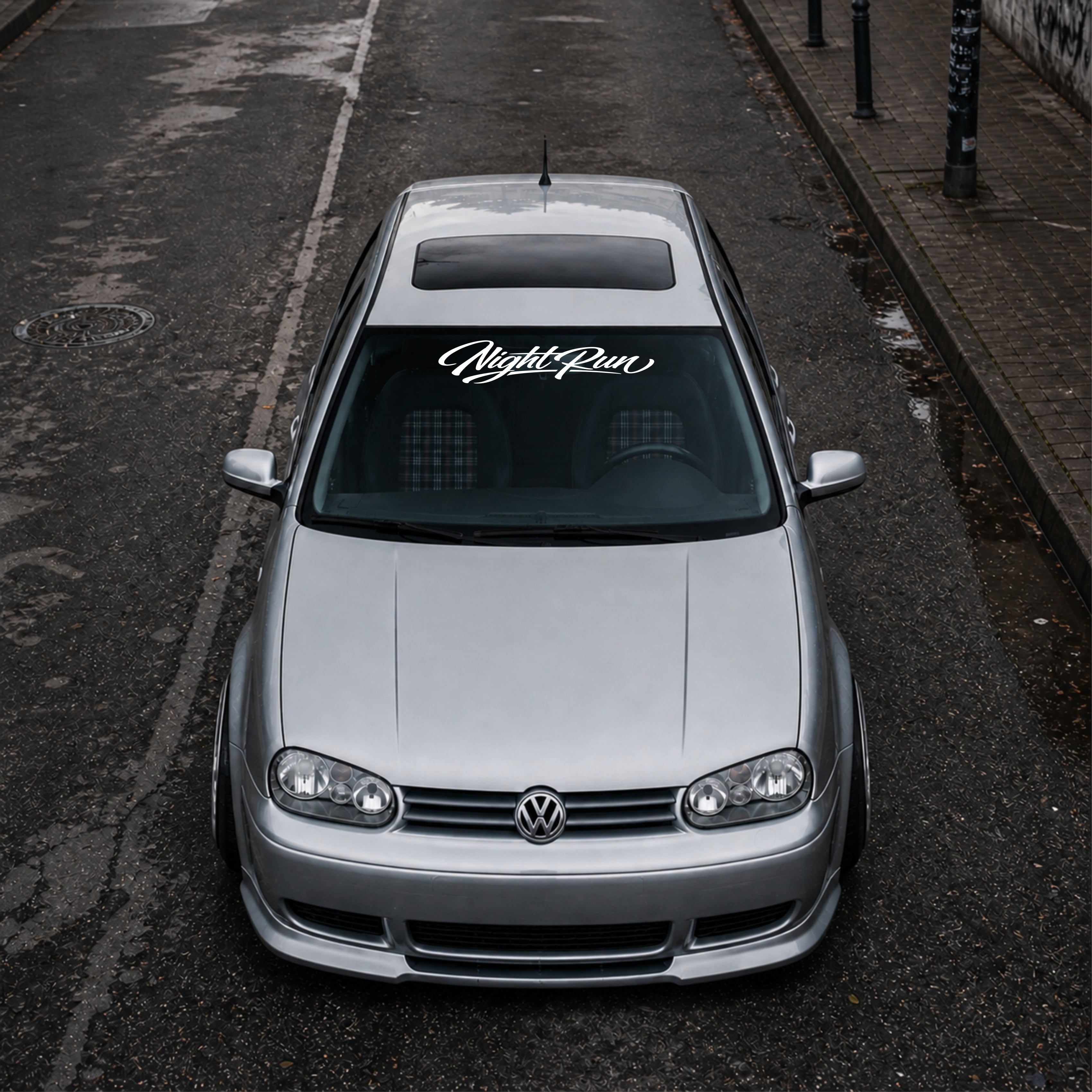 Silver Volkswagen car parked on an urban street with 'Night Run' decal.