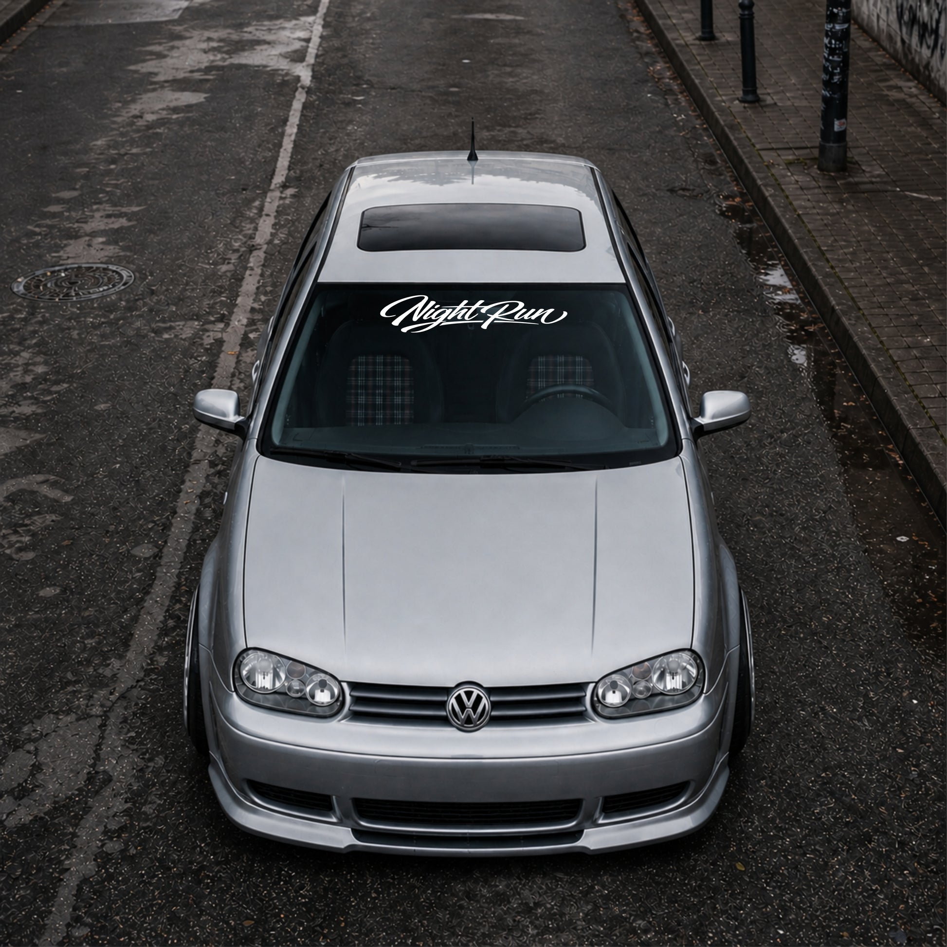 Silver Volkswagen car parked on an urban street with 'Night Run' decal.
