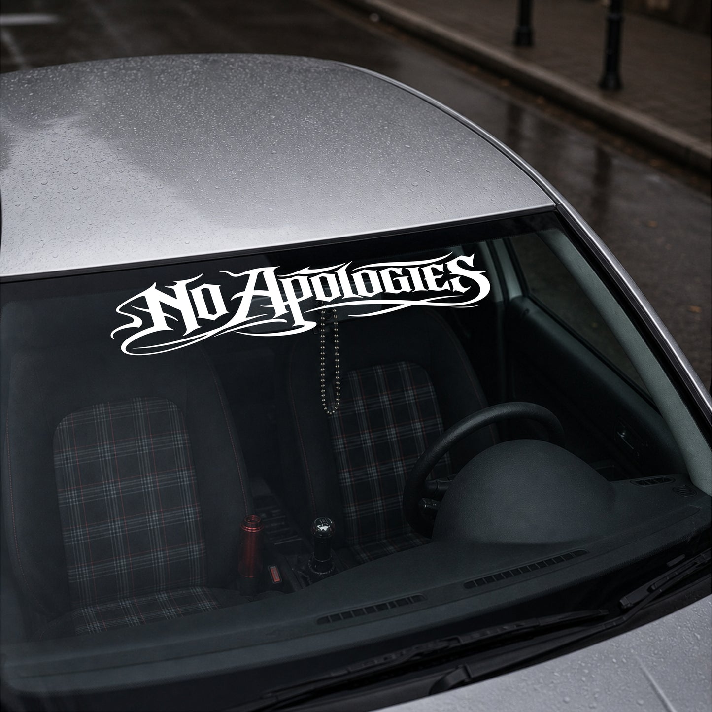 Car window with 'No Apologies' decal on a gray car.