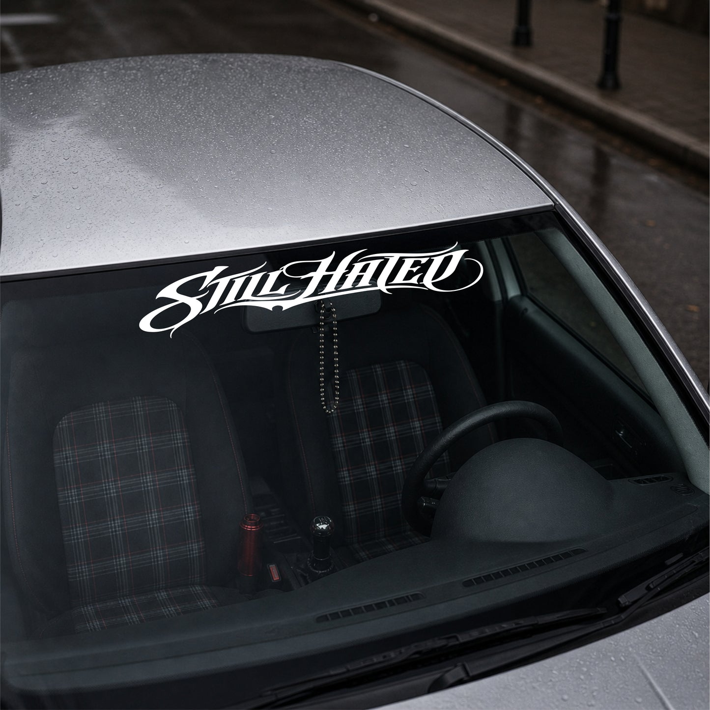 Car with 'Still Hated' decal on the windshield
