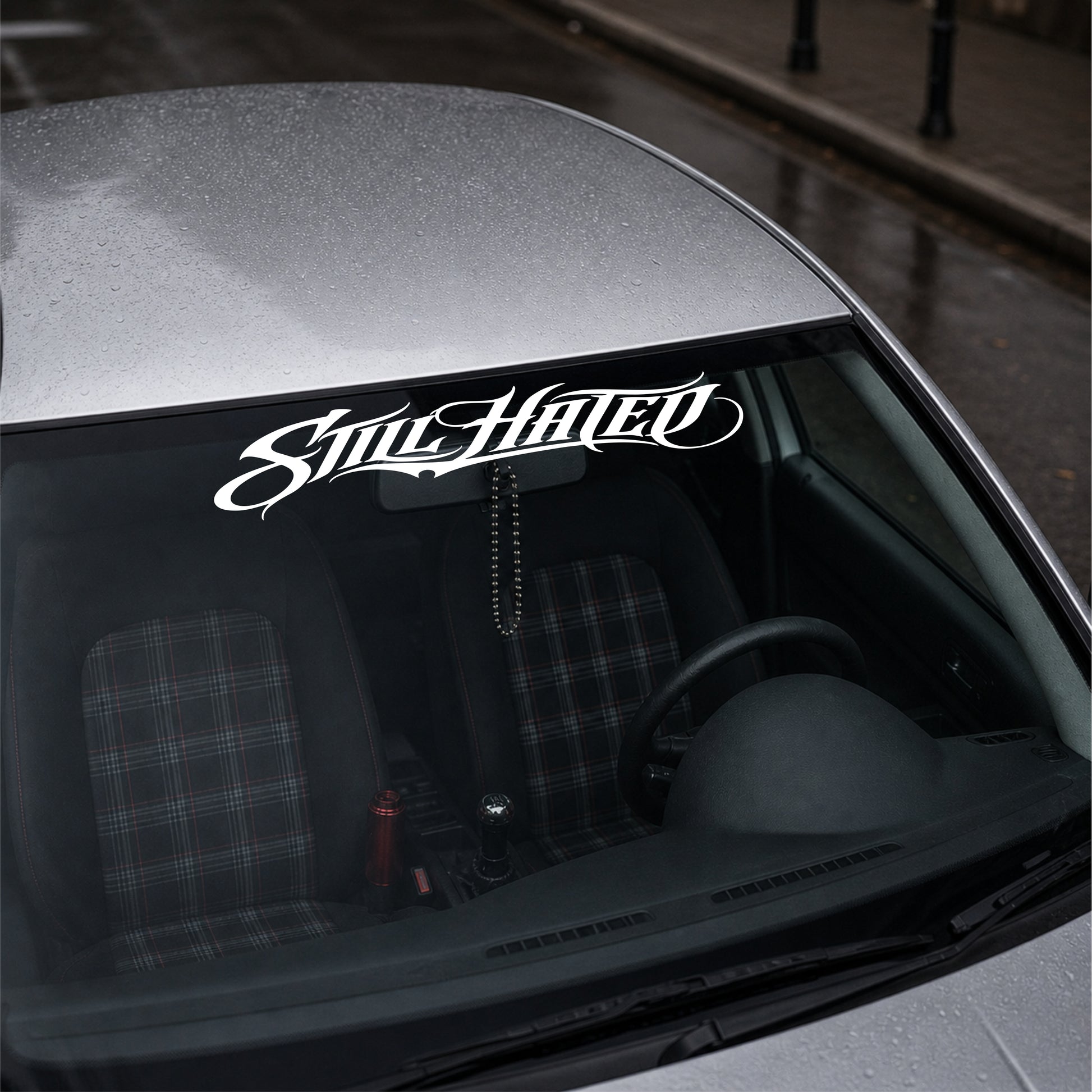 Car with 'Still Hated' decal on the windshield