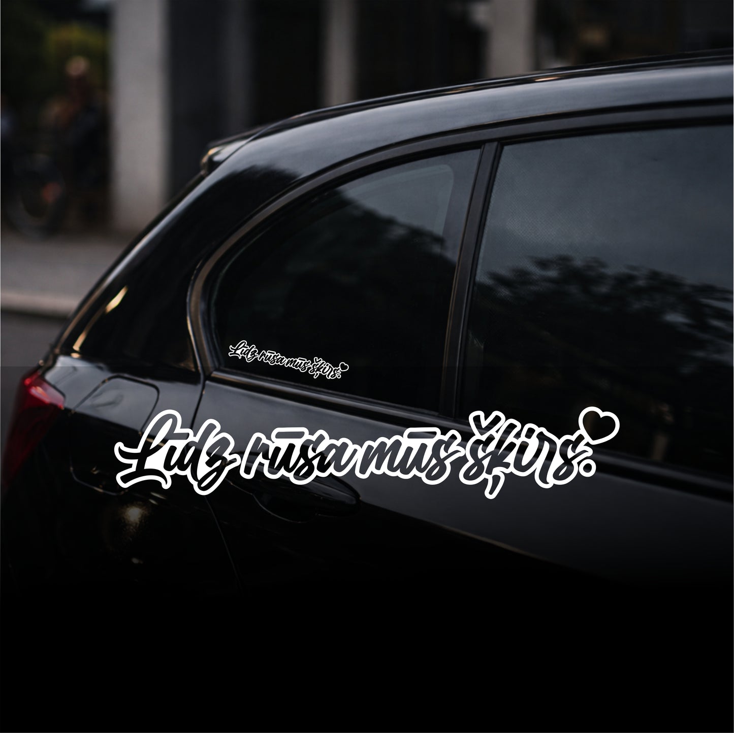 Black car with white text decal on a blurred street background