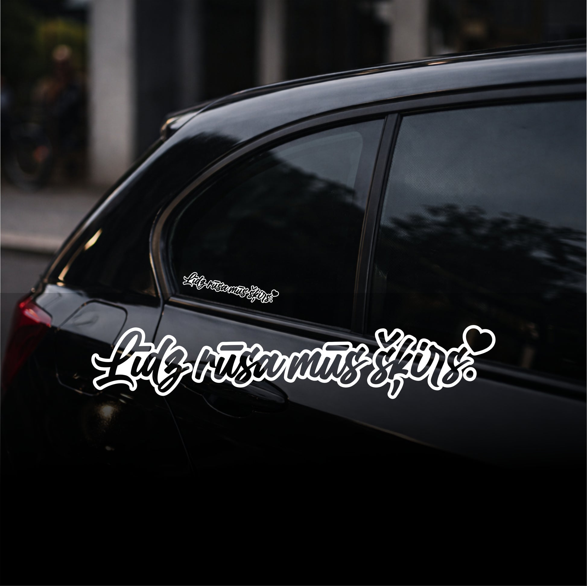 Black car with white text decal on a blurred street background