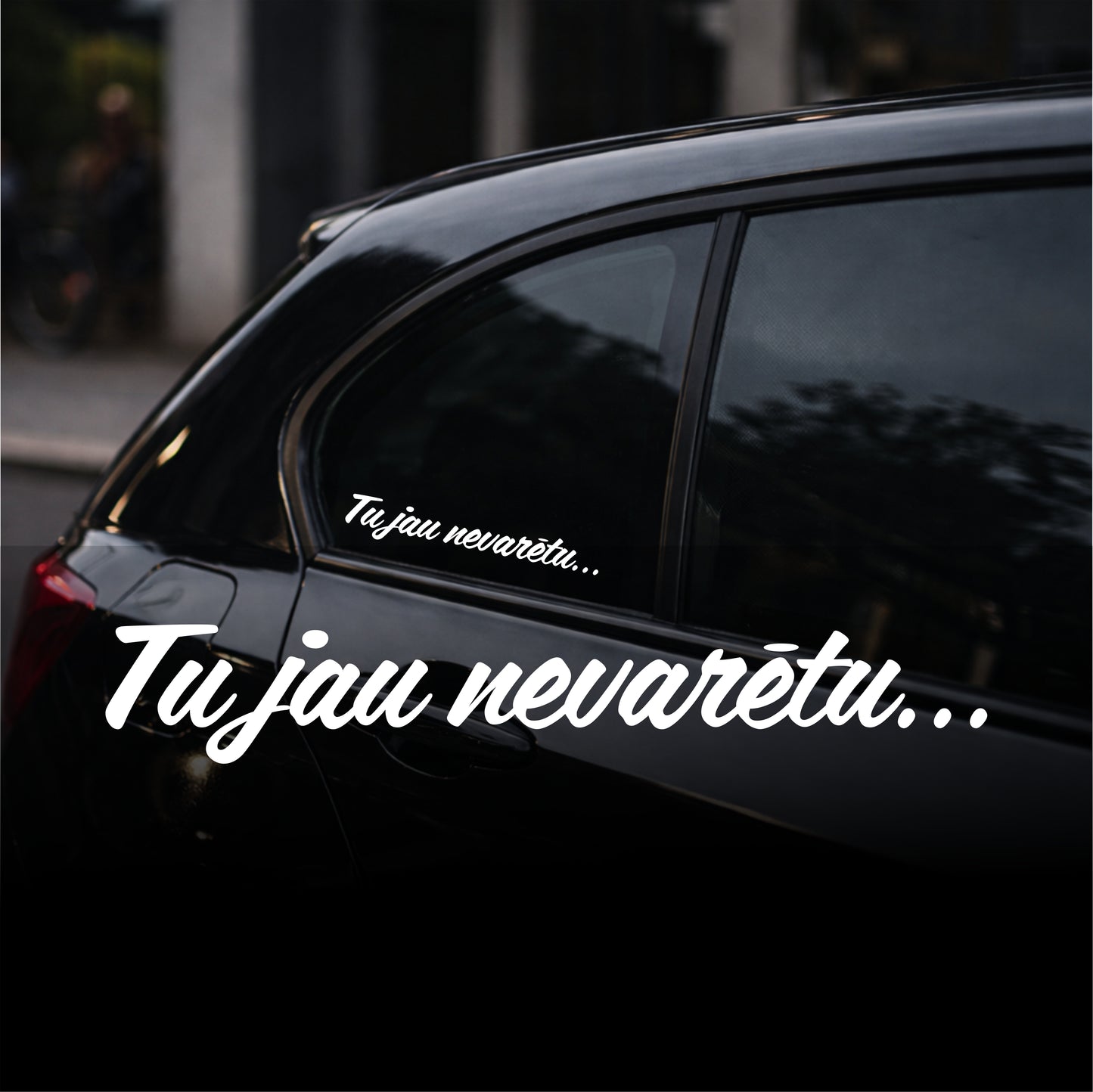 Black car with white text decal on a blurred street background