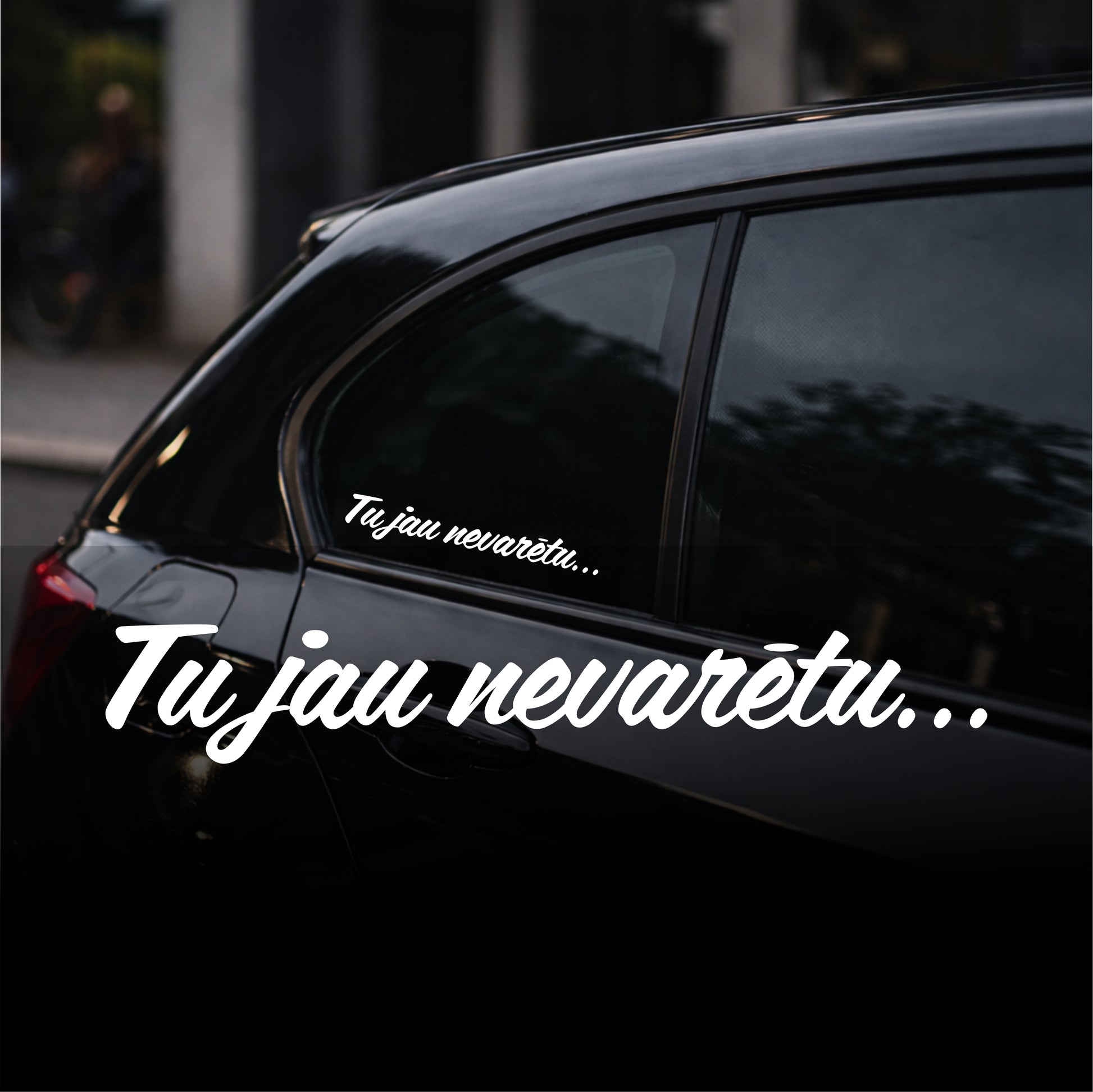 Black car with white text decal on a blurred street background