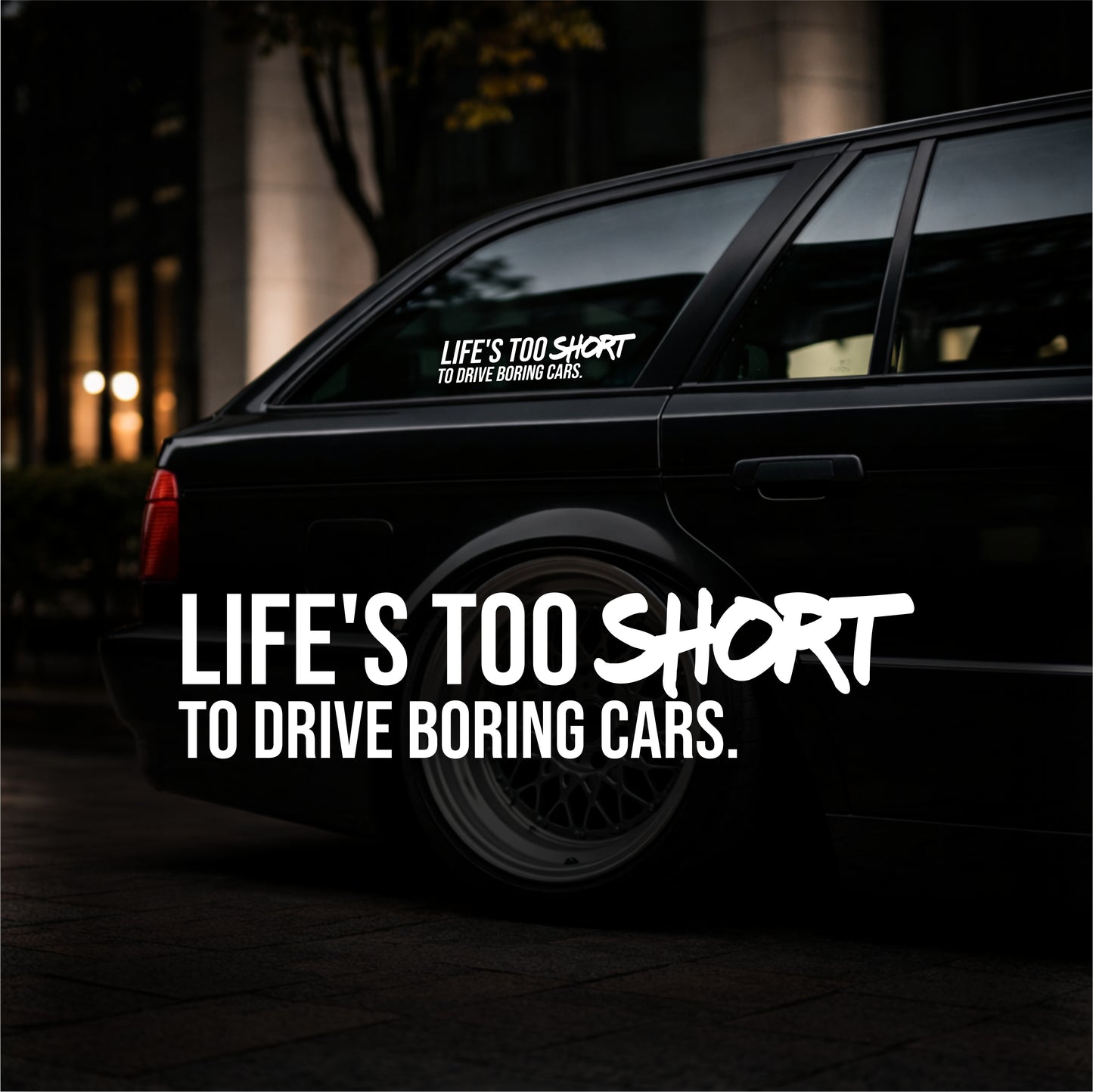 Black car with a motivational sticker on the back window at night.