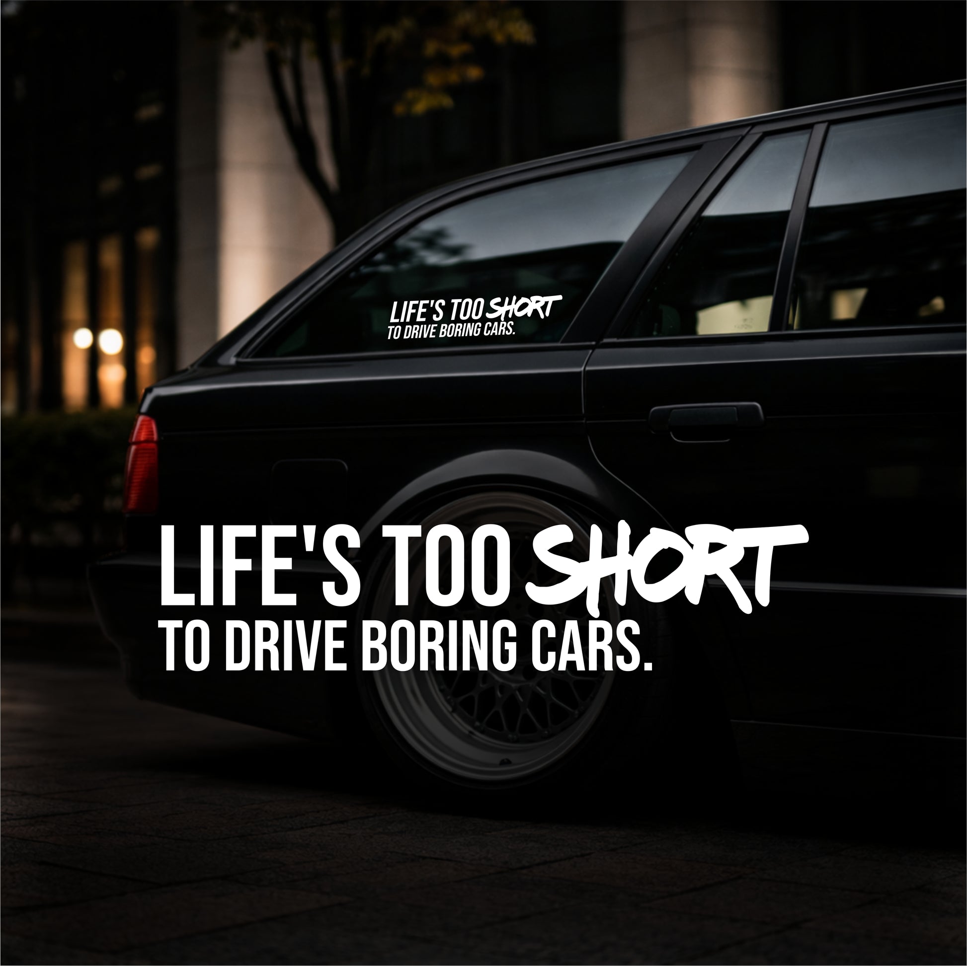 Black car with a motivational sticker on the back window at night.