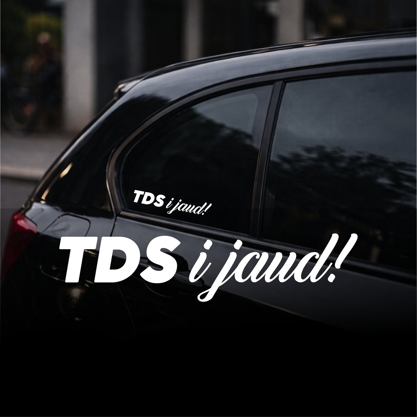 Black car with 'TDS i jaud!' decal on a blurred street background