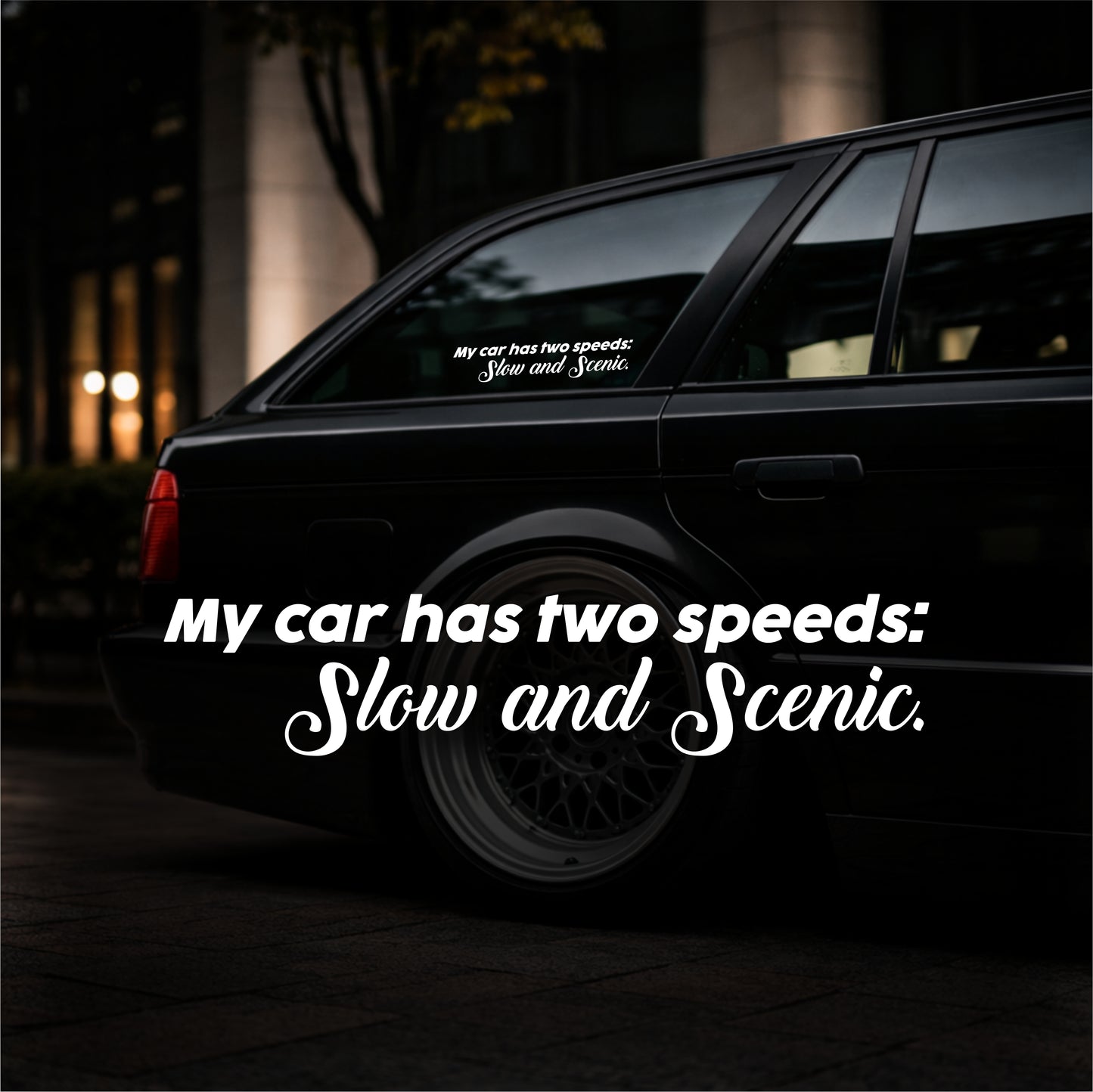 Black car with a humorous decal on the window at night.
