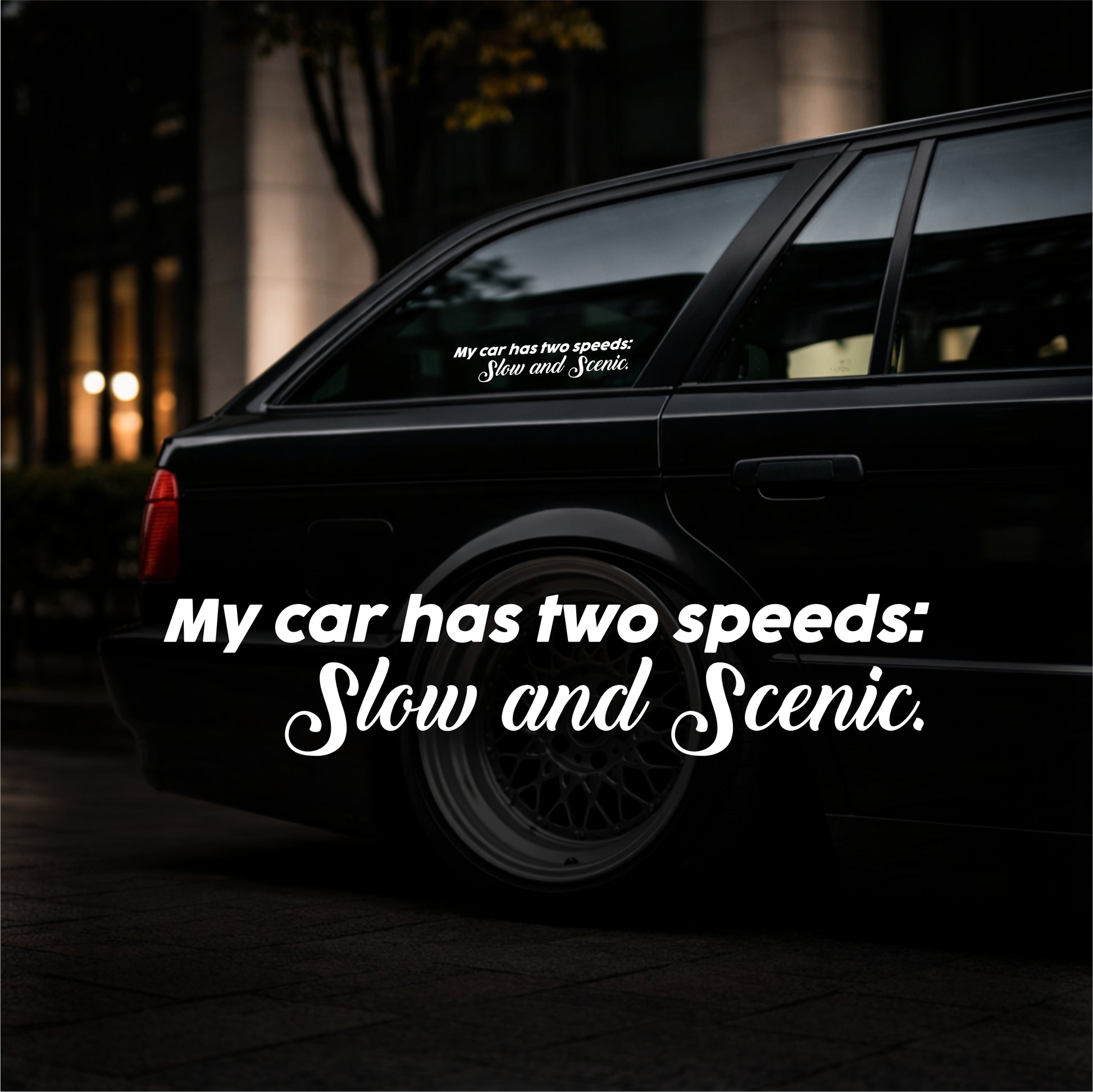 Black car with a humorous decal on the window at night.