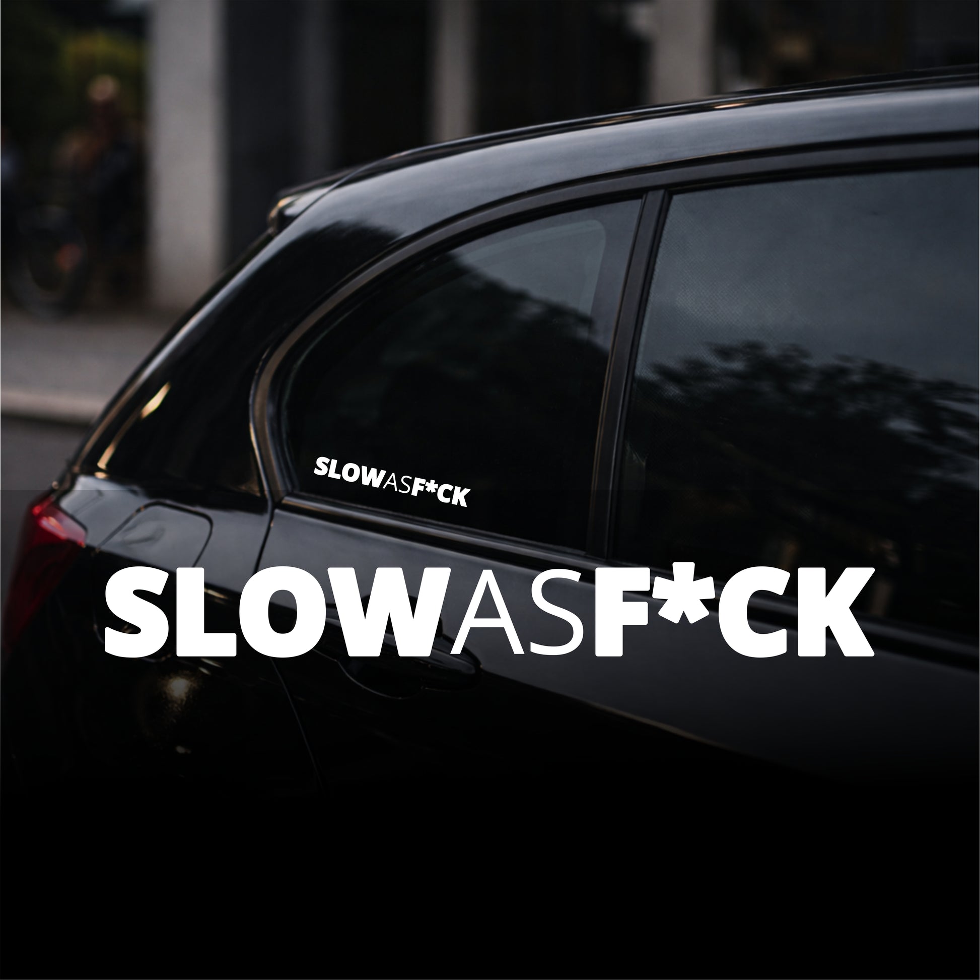 Black car with 'SLOWASF*CK' decal on a blurred street background