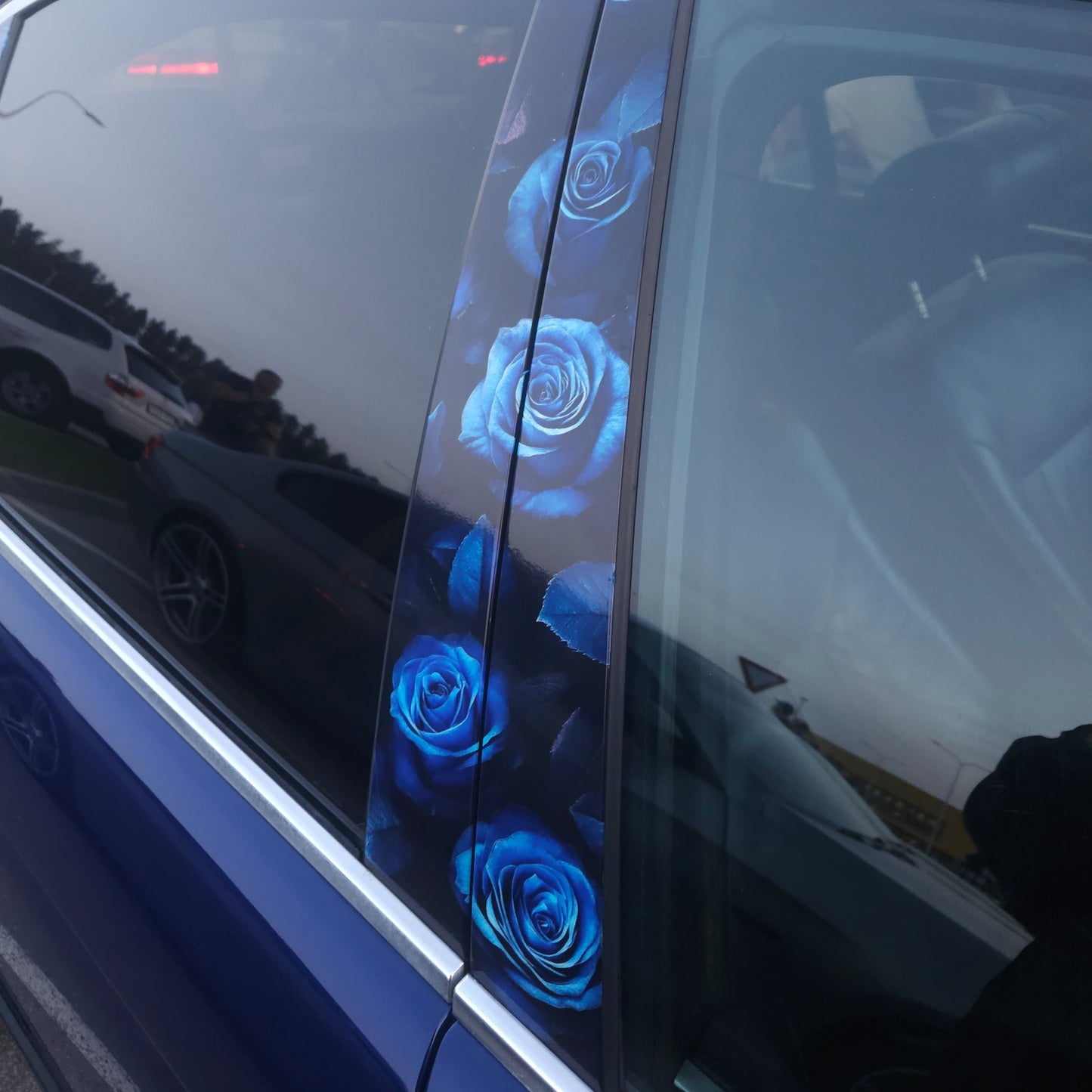 Close-up of a car's side mirror with blue lights reflecting on it.