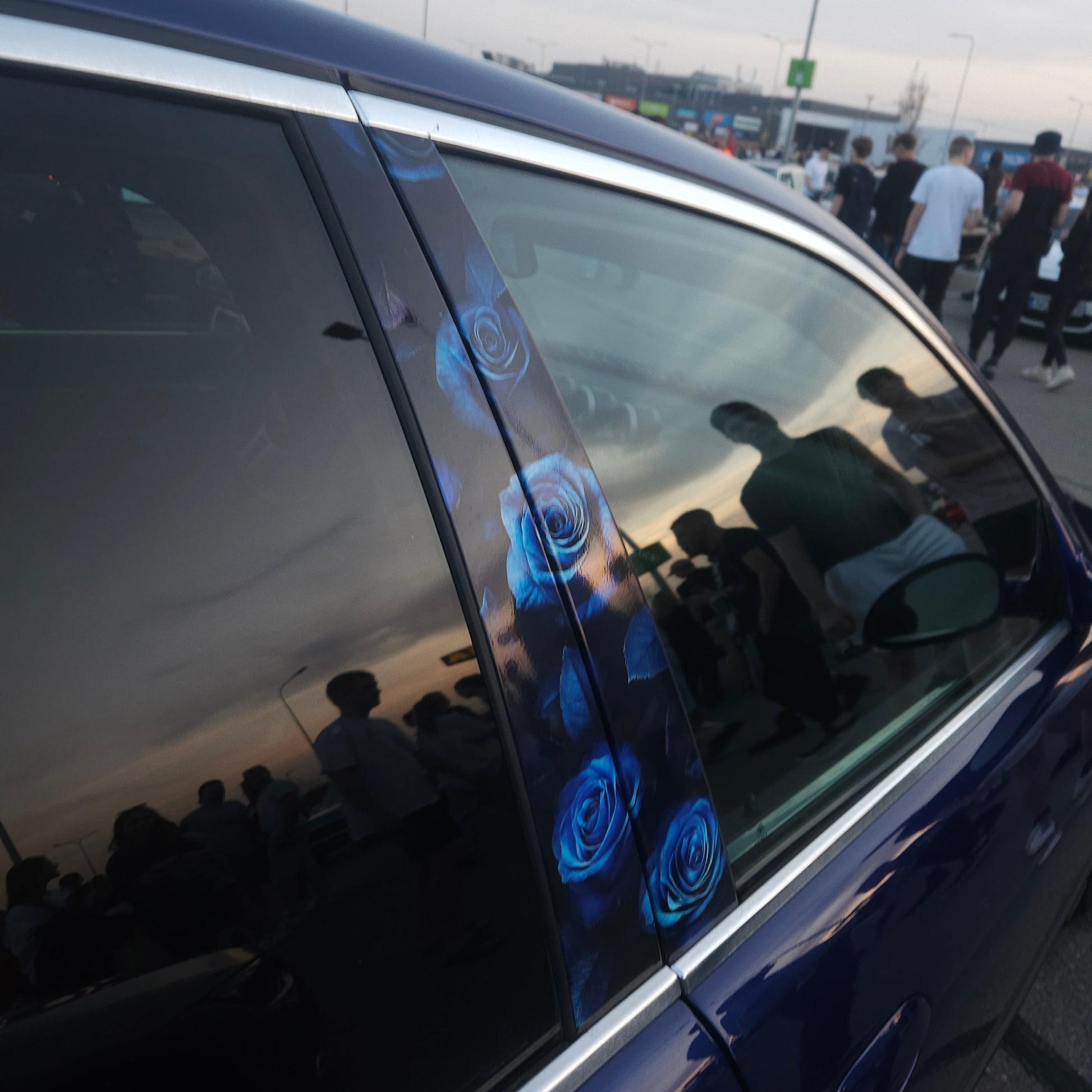 Car window with blue flower-shaped objects on a reflective surface