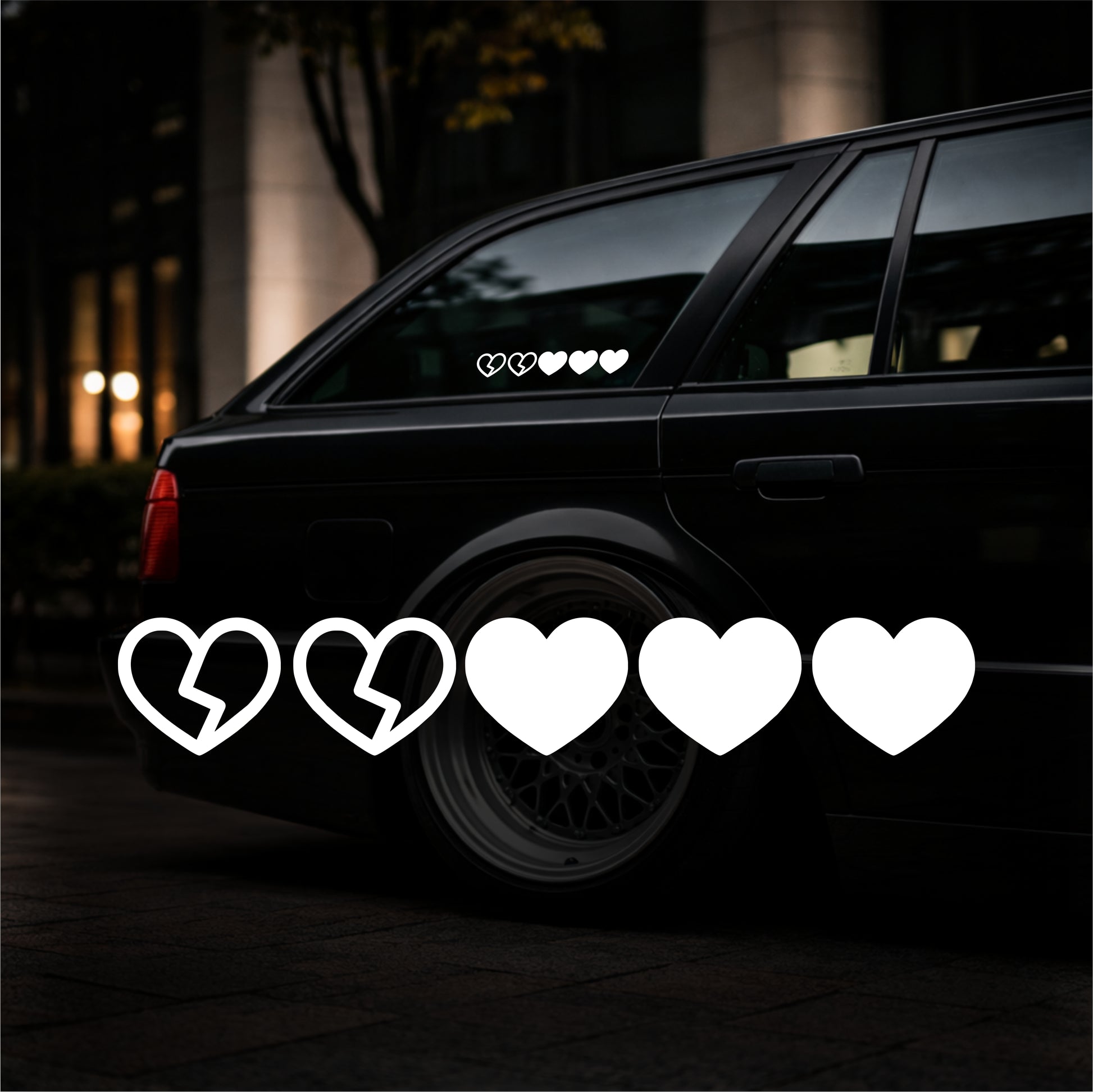 Black car with heart-shaped decals on a dark background