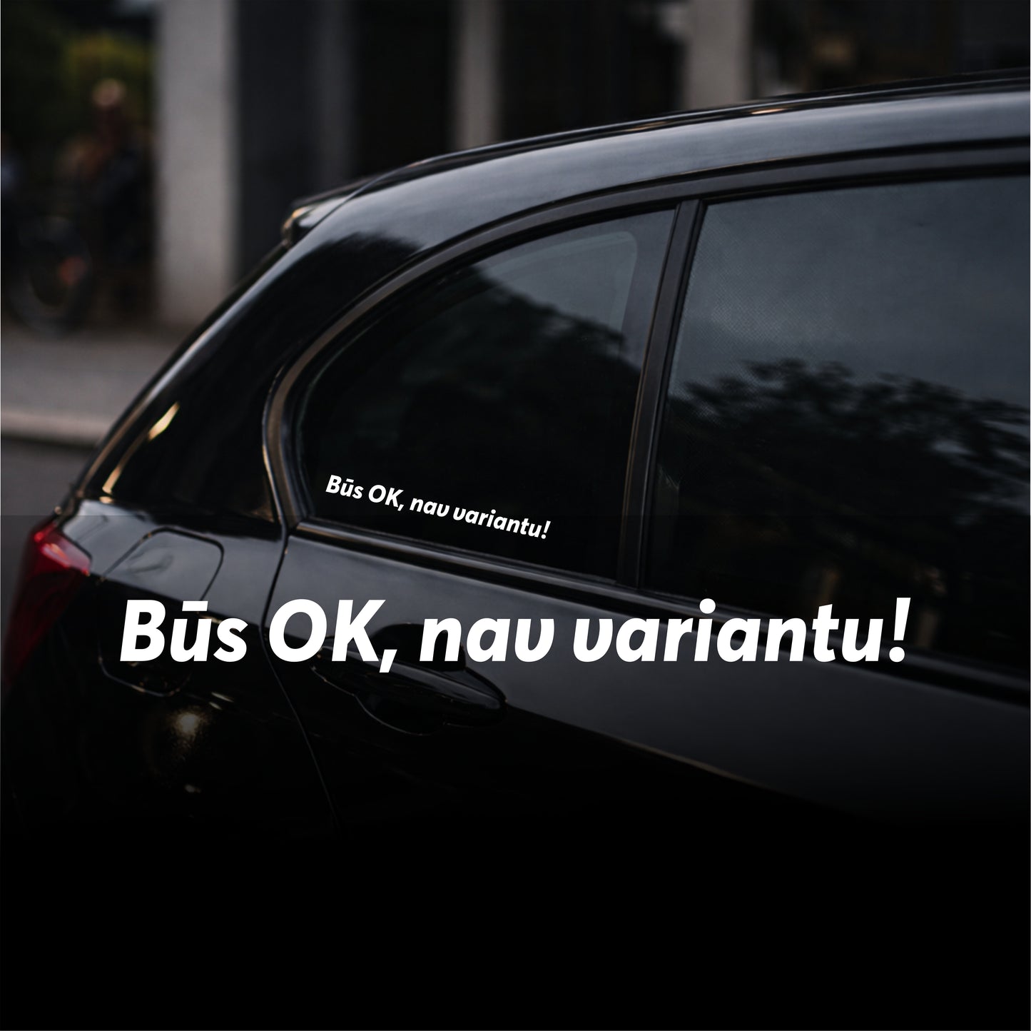 Black car with a humorous sticker on the window in a blurred urban setting