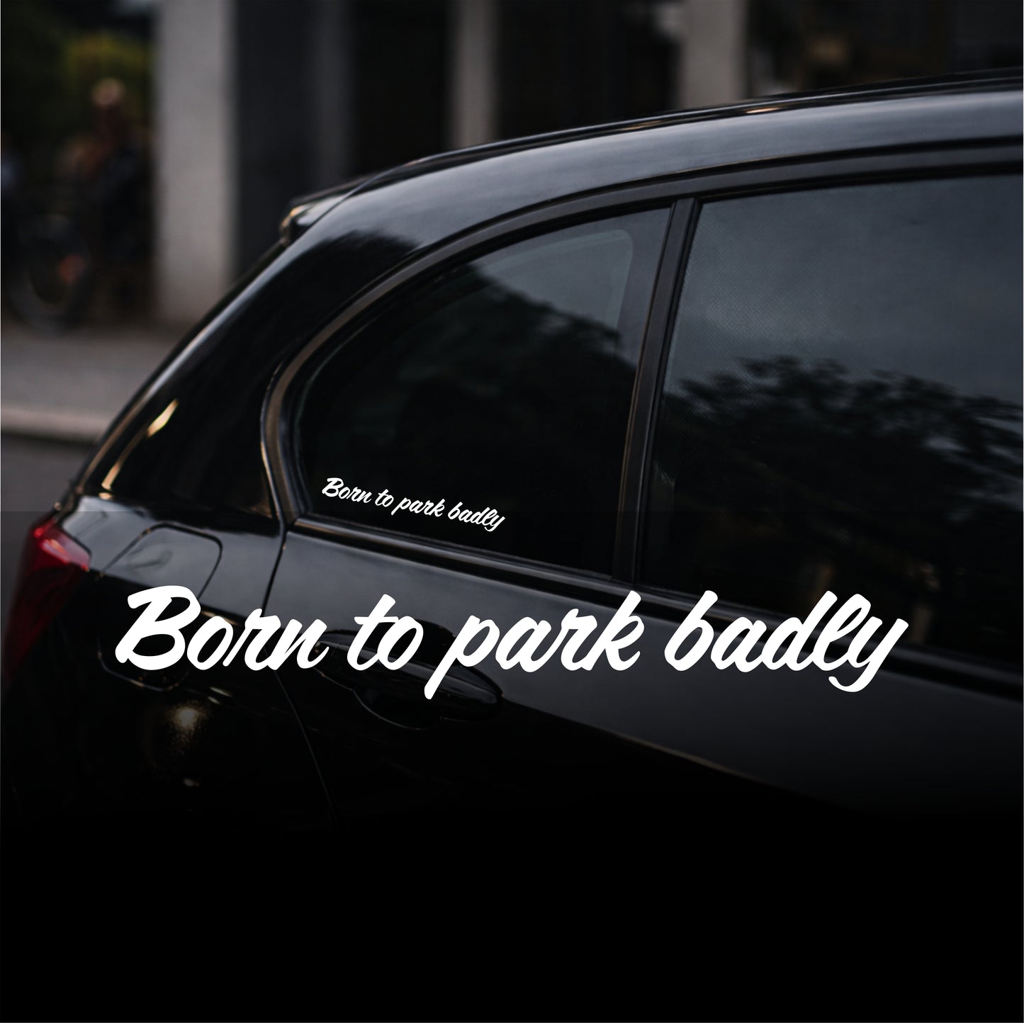 Black car with a humorous 'Born to park badly' sticker on a blurred street background