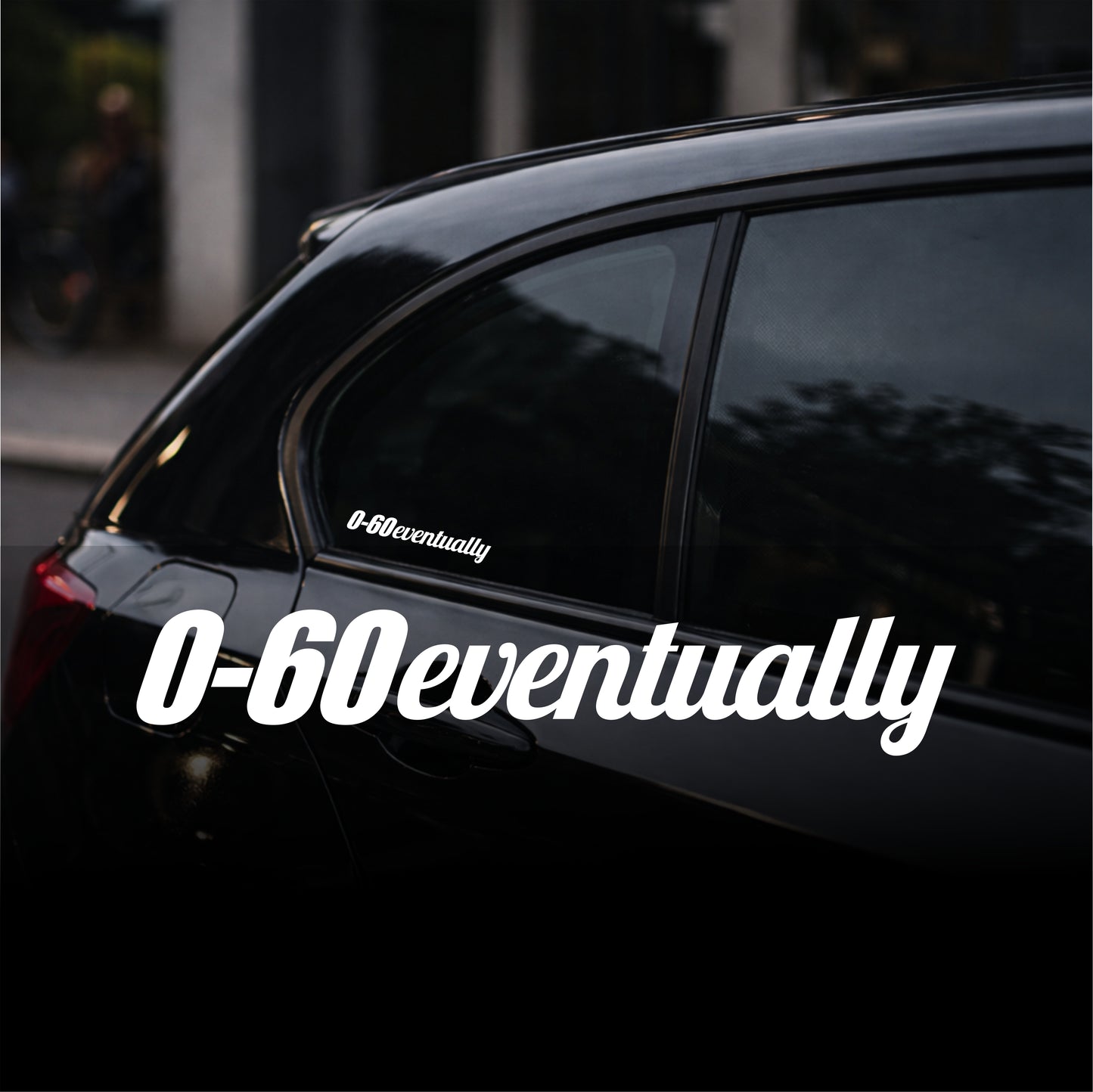 Black car with '0-60eventually' decal on a blurred street background