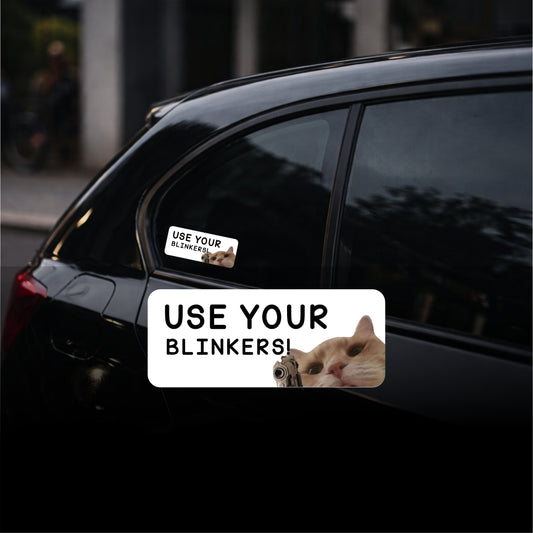 Car window with a humorous 'Use Your Blinkers!' sticker featuring a cat.