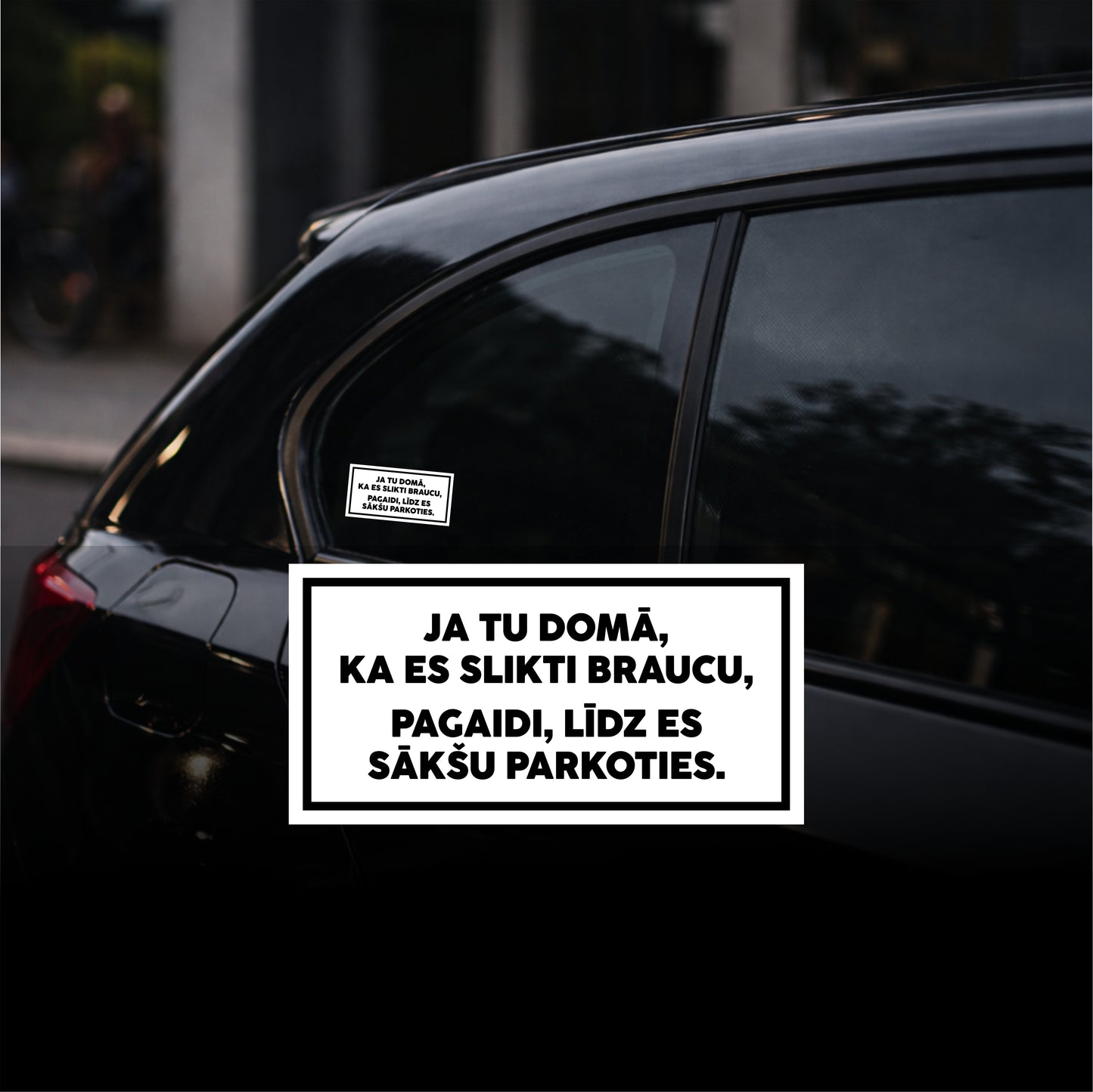 Car window with a sticker in a foreign language on a blurred street background