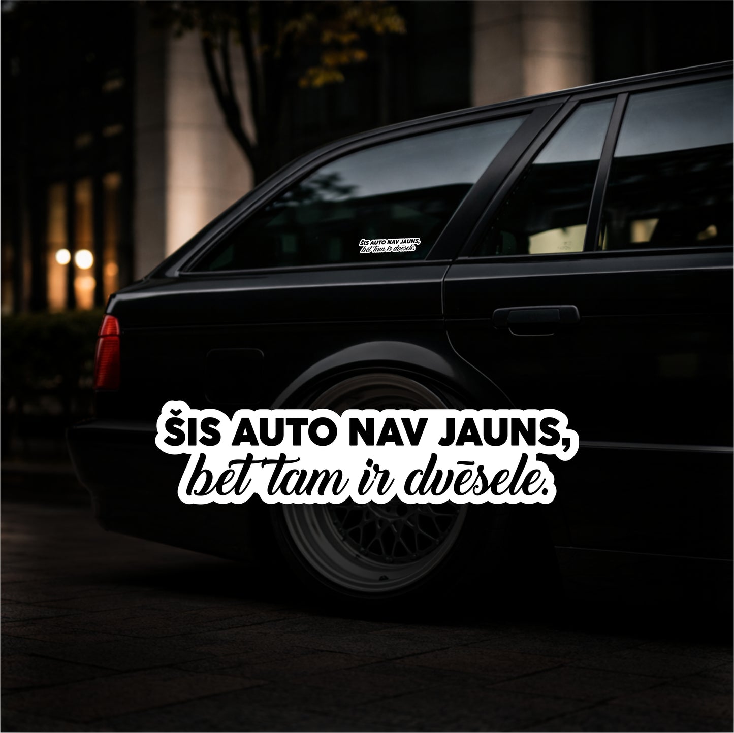 Black car with a humorous text sticker in a dark setting