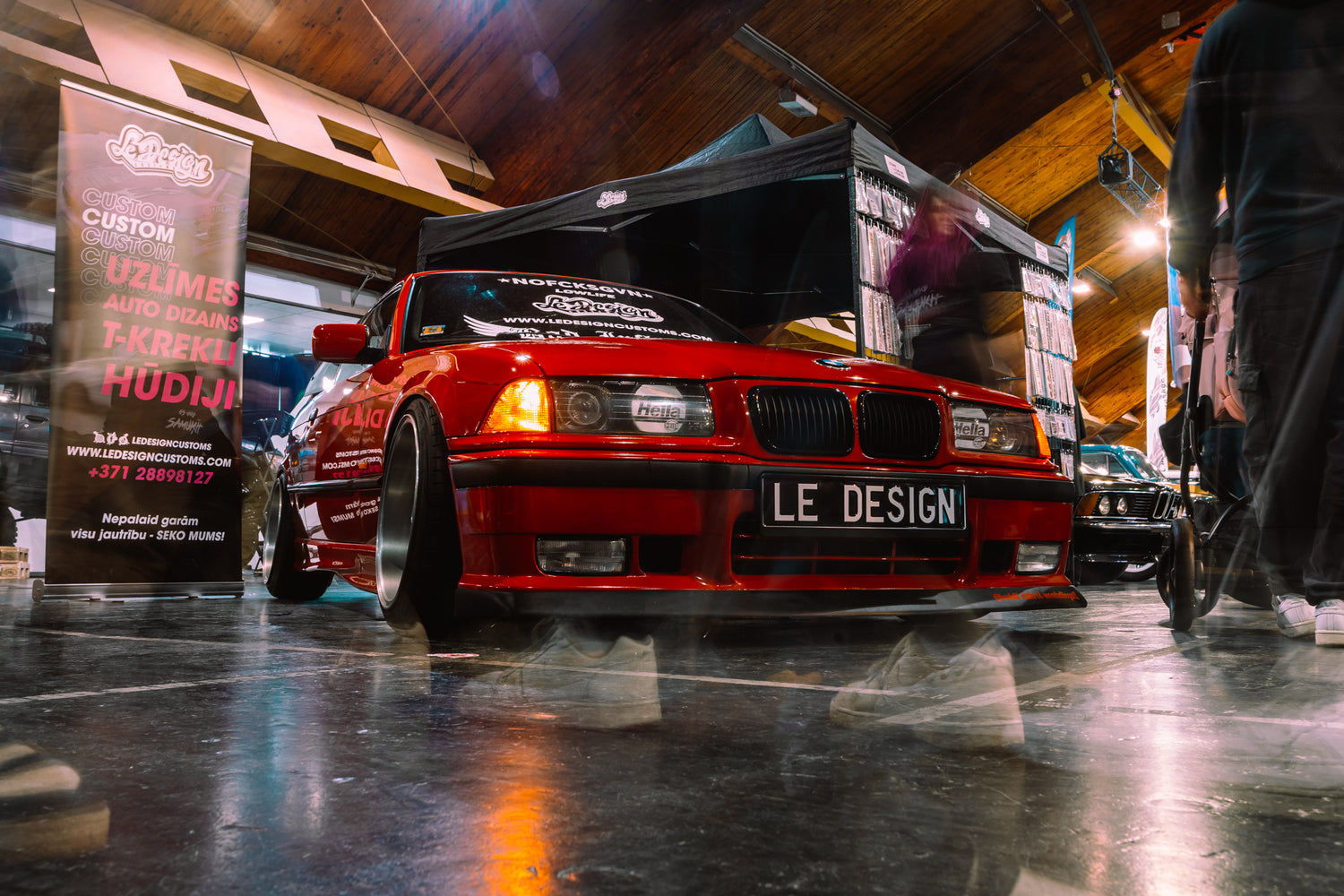 Red car with 'LE Design' on a black background in a garage setting