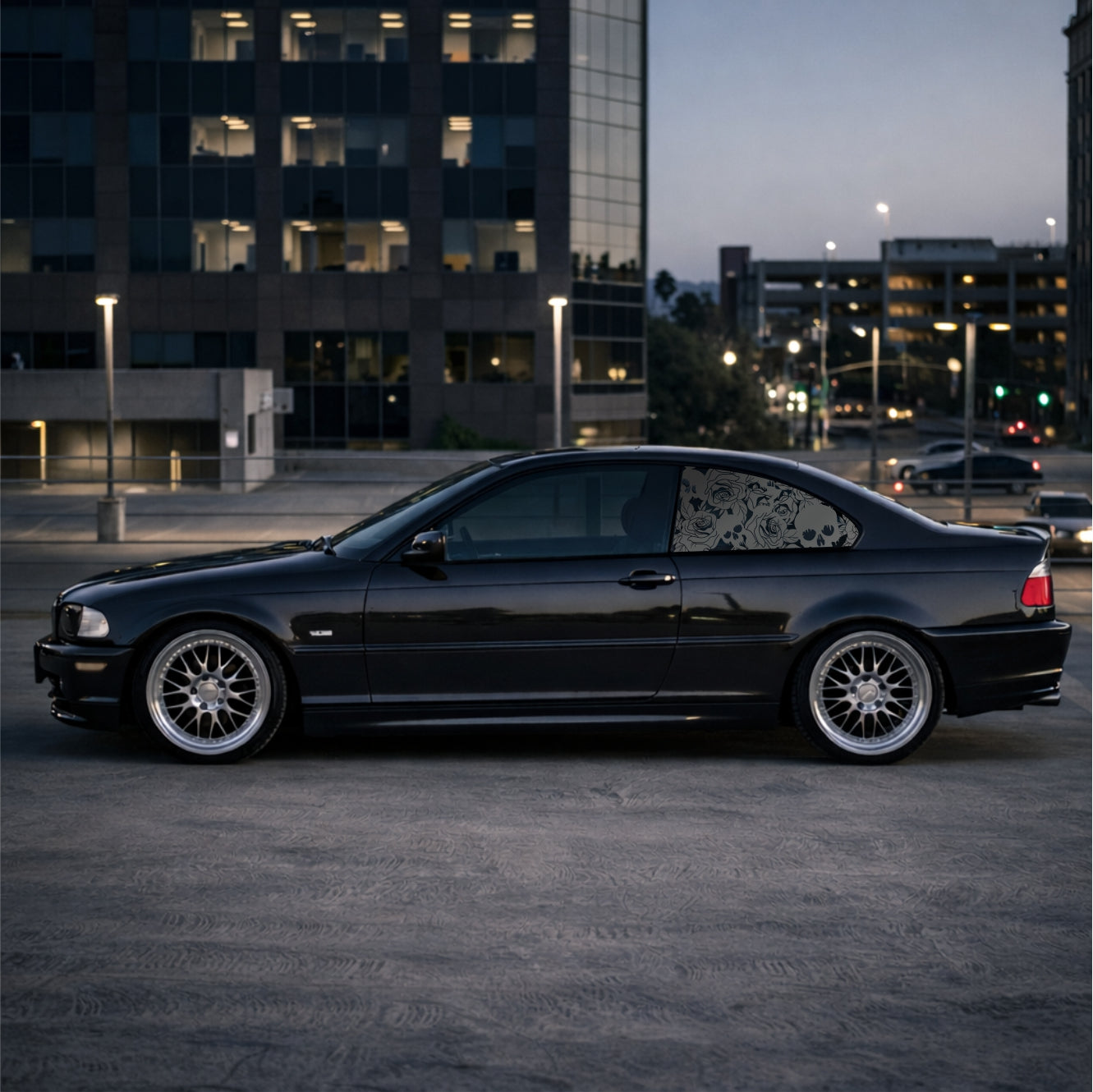 Black car parked in an urban setting at dusk with buildings in the background