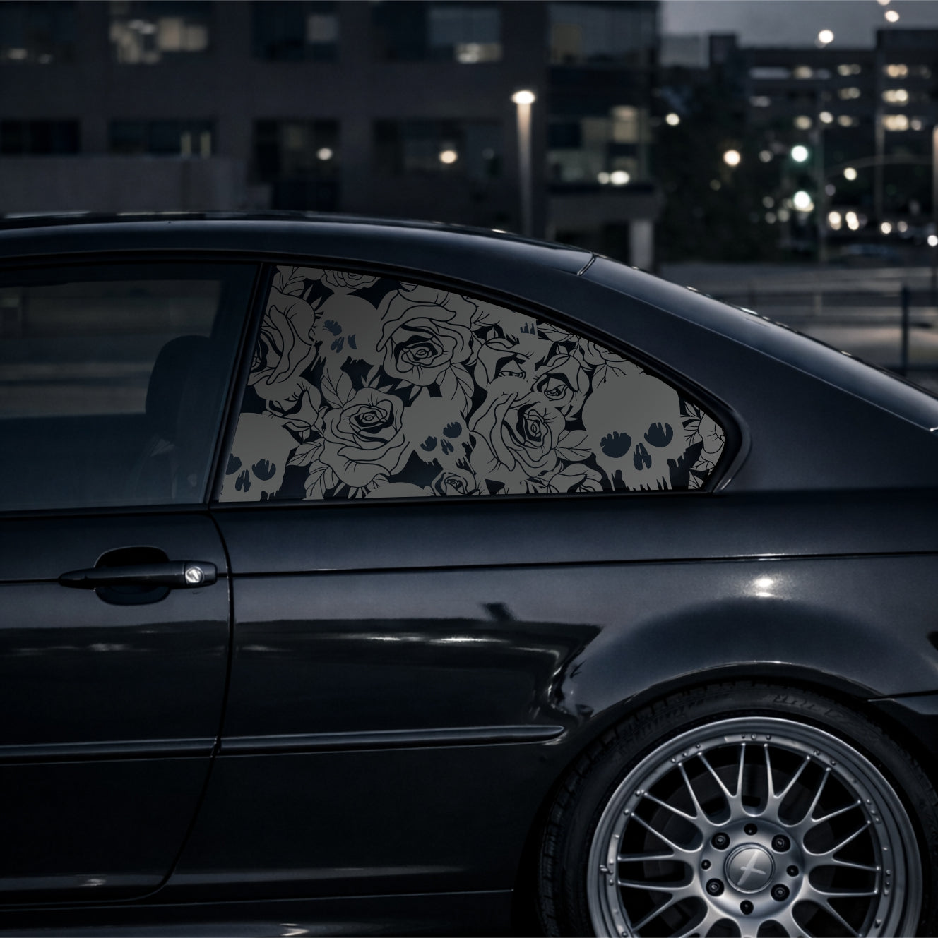 Black car with floral window decal at night in an urban setting