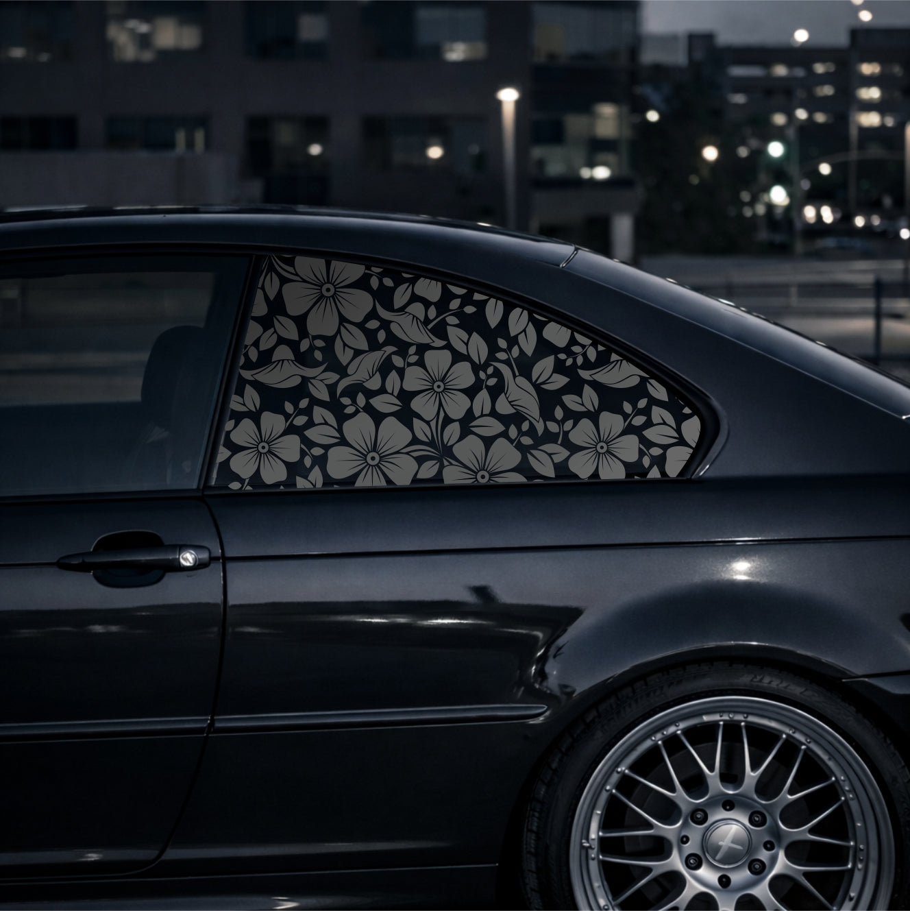 Black car with floral window decal in an urban setting at night