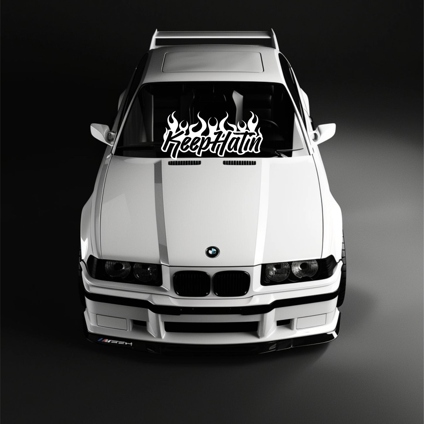 White BMW car with a 'Keep Itin' decal on the windshield against a black background