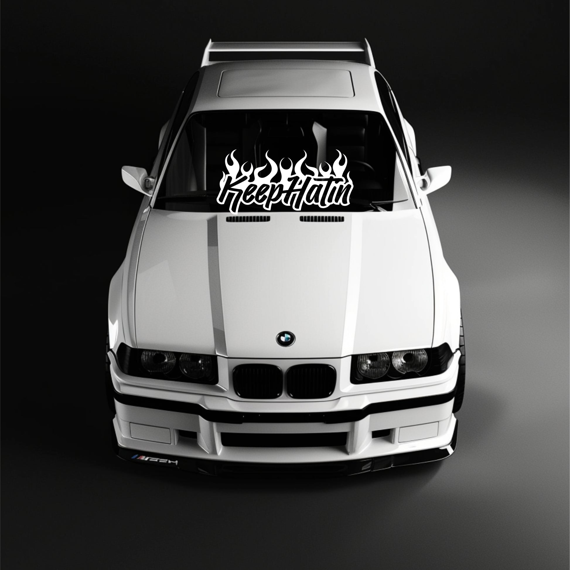 White BMW car with a 'Keep Itin' decal on the windshield against a black background