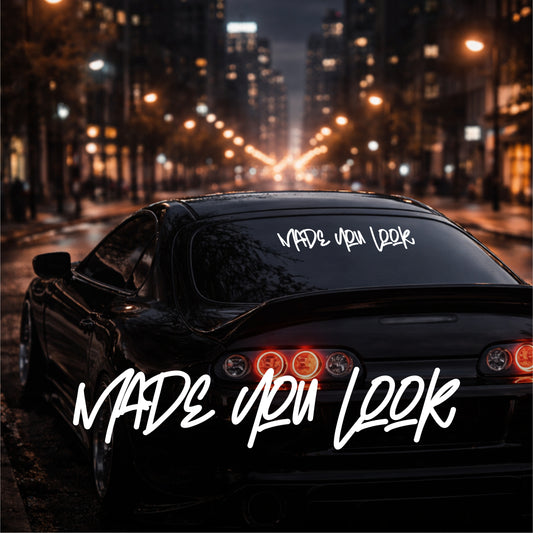 Car with 'MADE YOU LOOK' decal on a city street at night