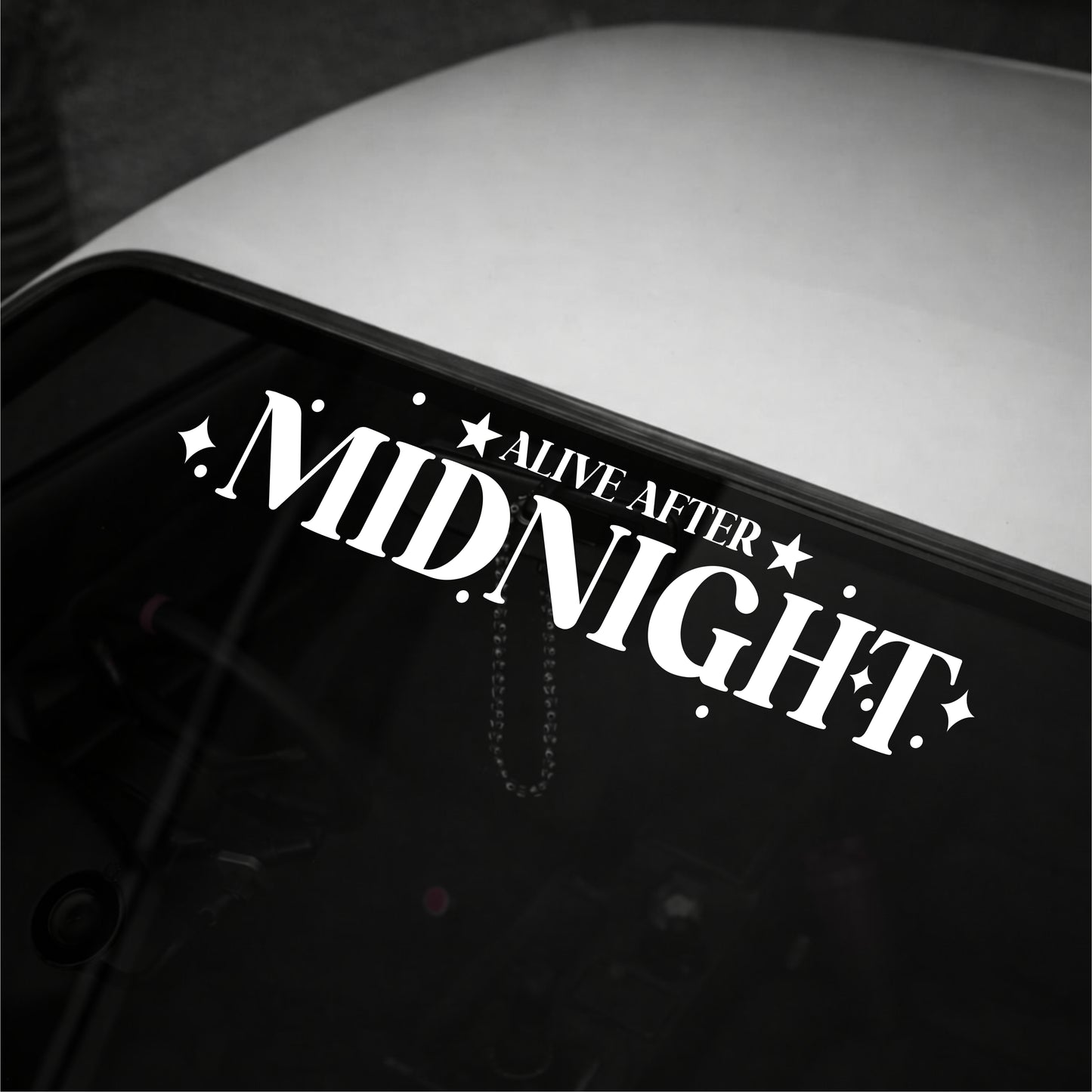Decal with 'Alive After Midnight' text on a vehicle's window.
