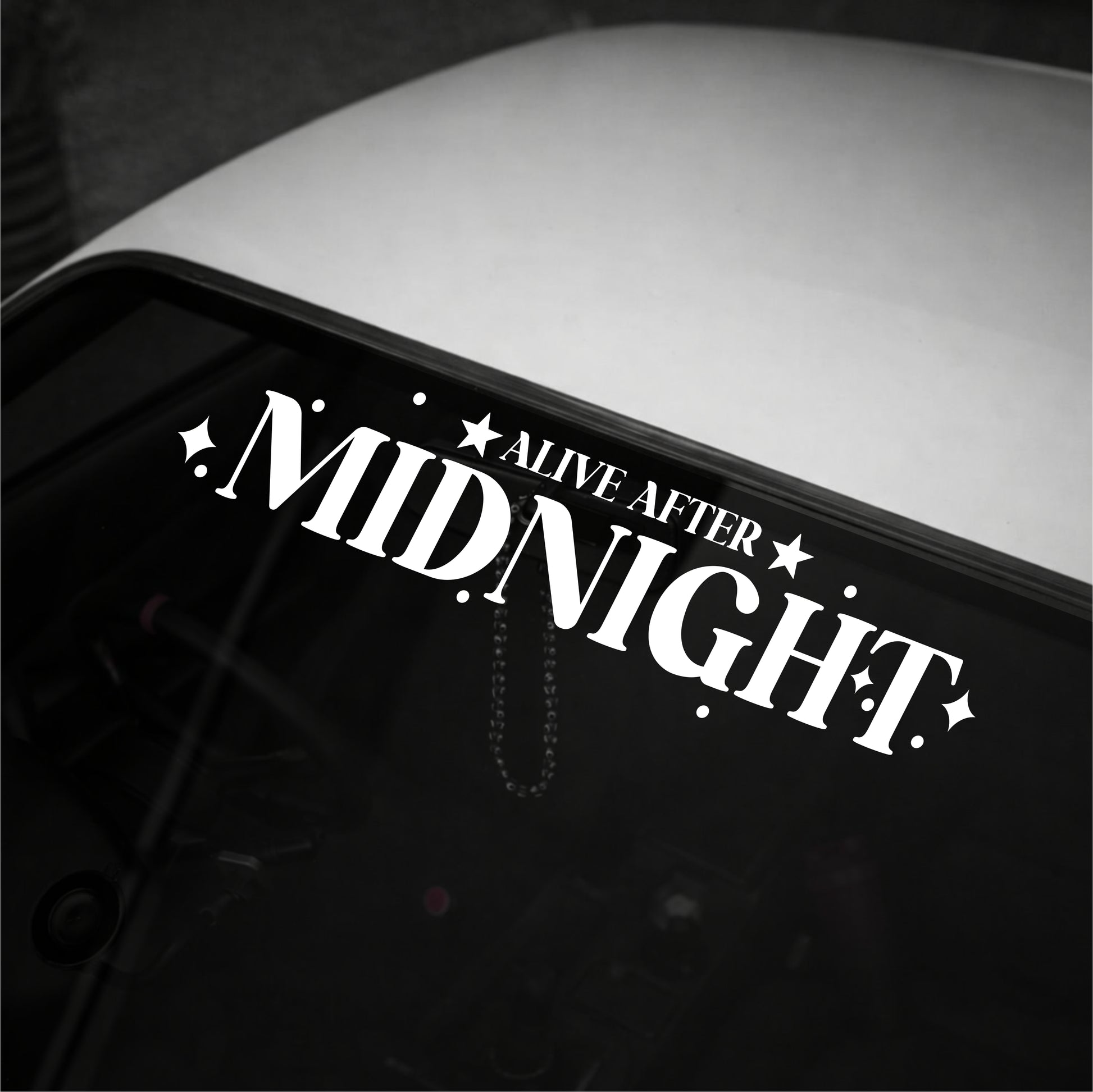Decal with 'Alive After Midnight' text on a vehicle's window.