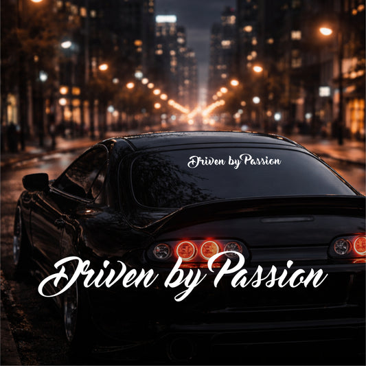 Car with 'Driven by Passion' decal on a city street at night