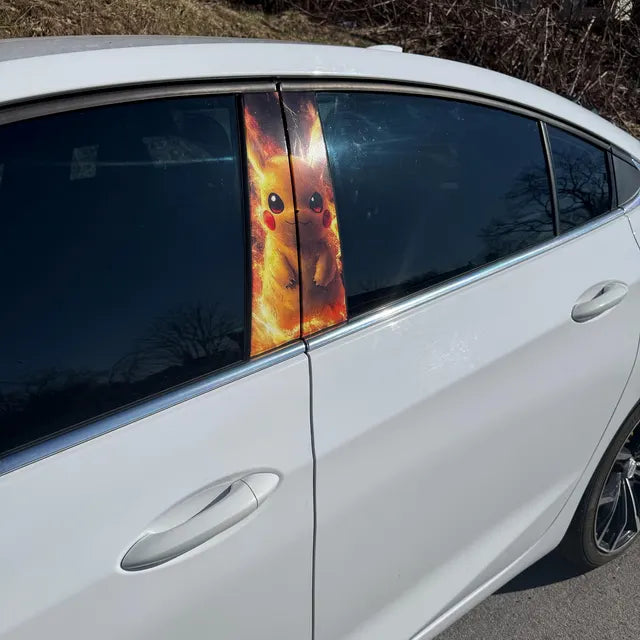 Car window with a cartoon character decal on a white car outdoors.